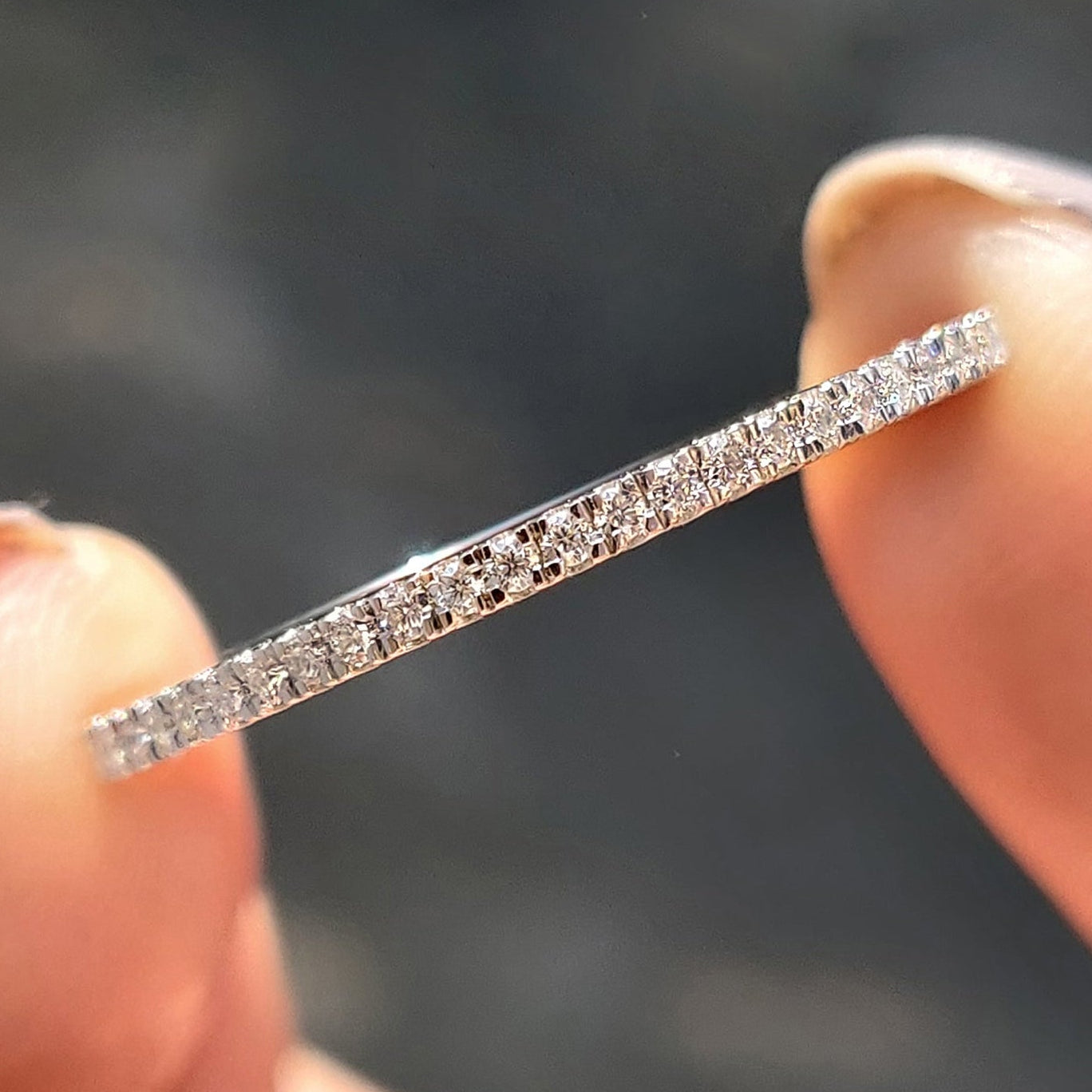 White gold eternity band with round moissanite stones.