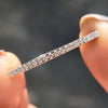 White gold eternity band with round moissanite stones.