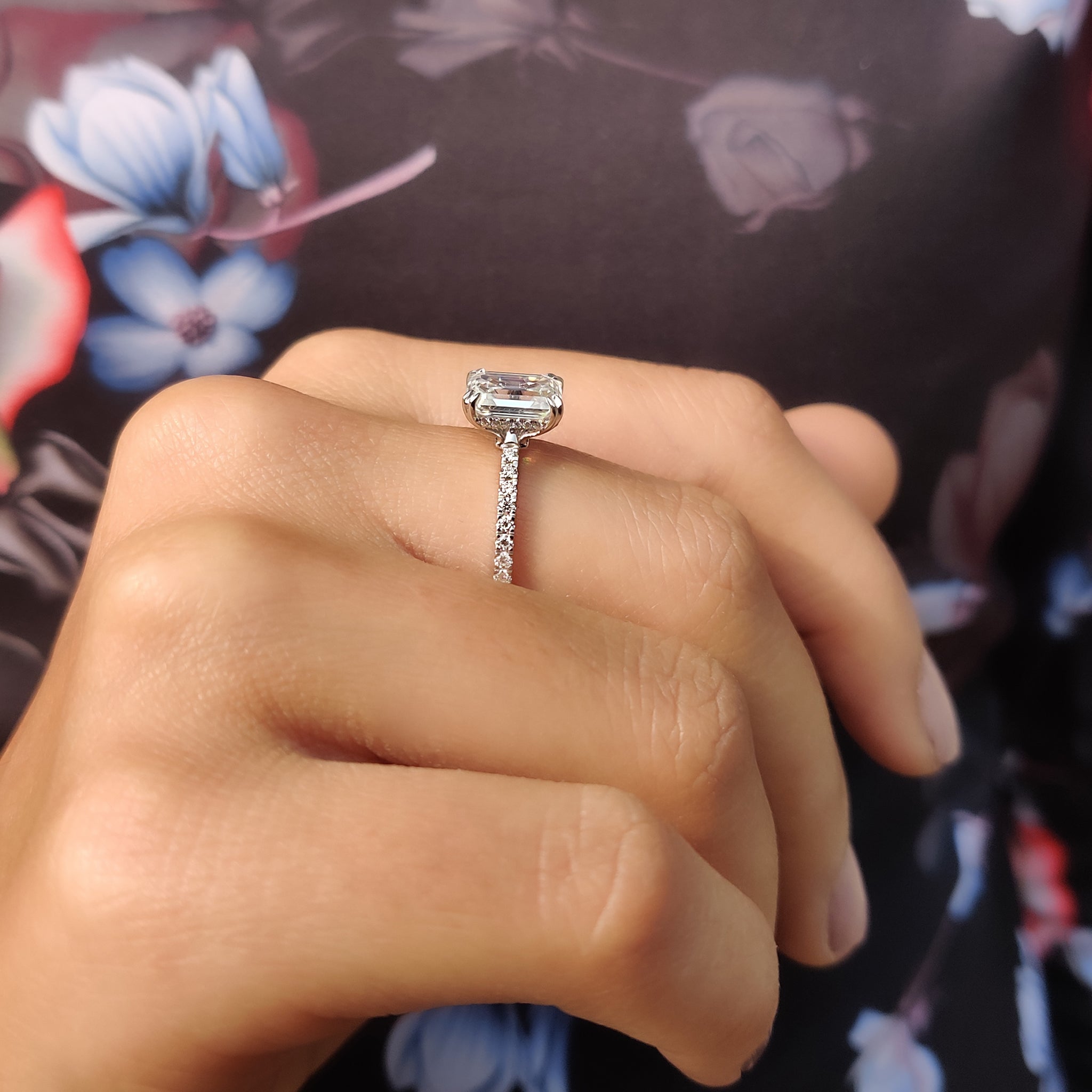 Pave setting ring featuring an emerald cut moissanite stone.
