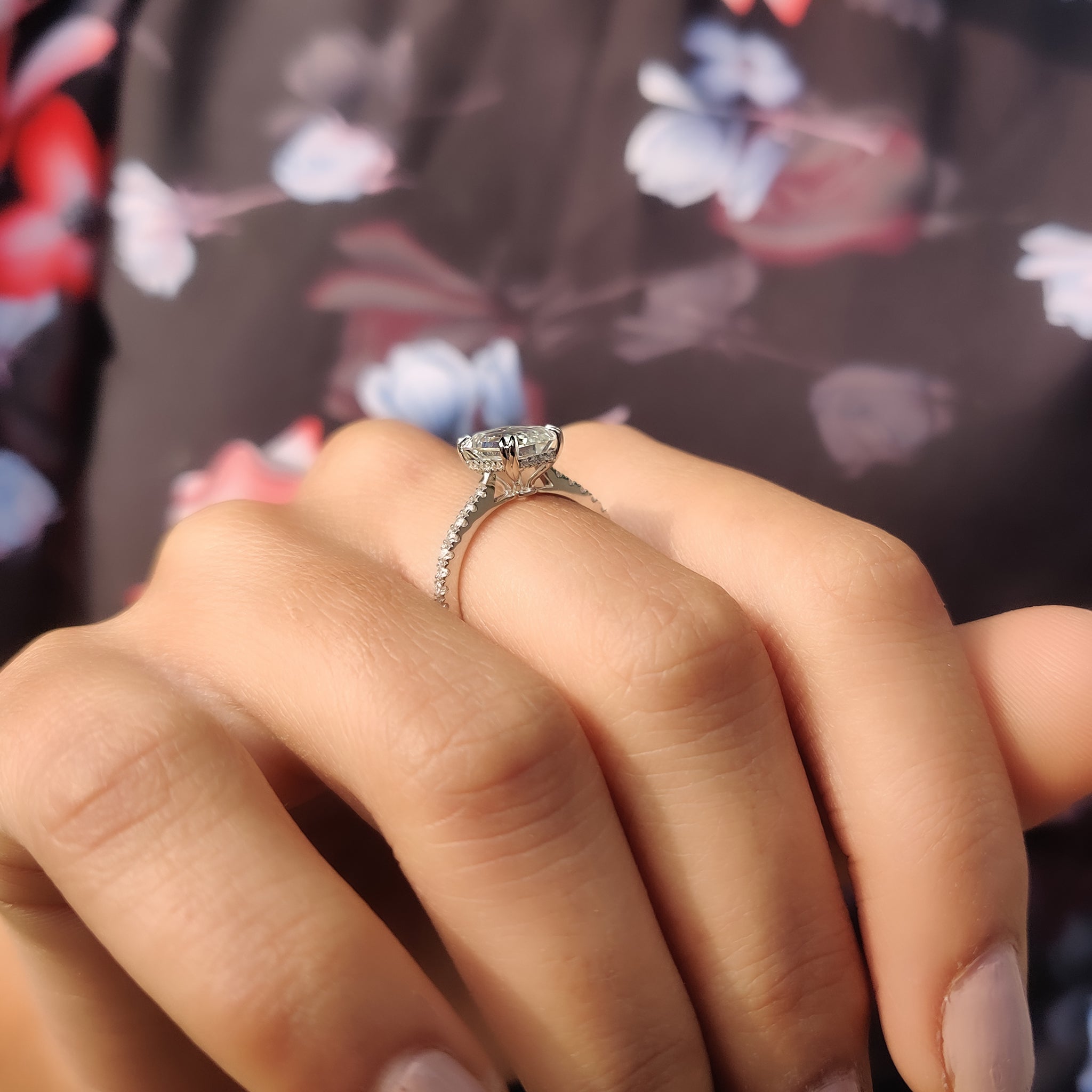White gold ring with a round cut pave setting and emerald moissanite.
