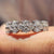 Round cut wedding band crafted in white gold with leaf-inspired garland pattern.
