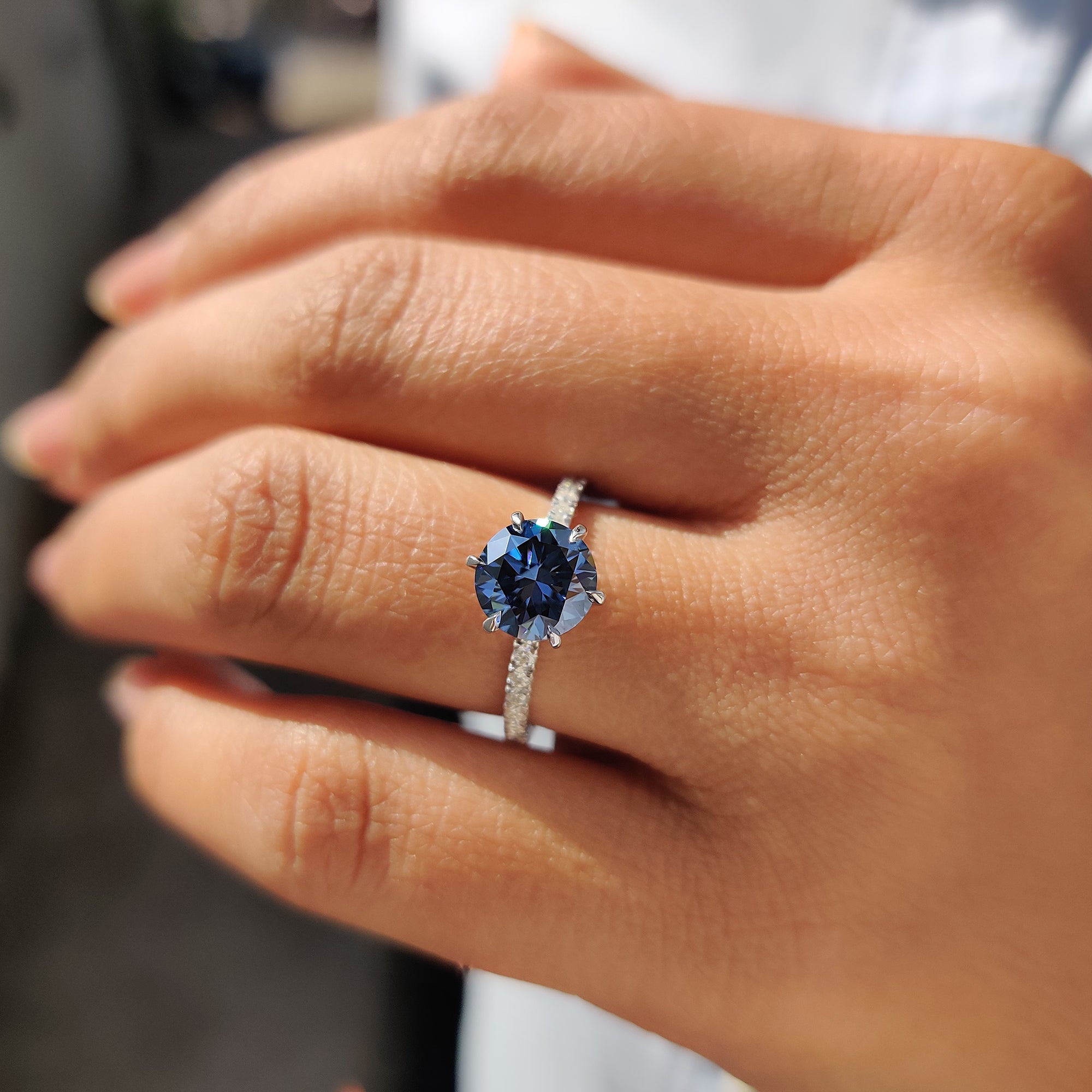 6 claw prong setting on a round cut pave band, featuring royal dark blue Moissanite.
