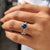 6 claw prong setting on a round cut pave band, featuring royal dark blue Moissanite.

