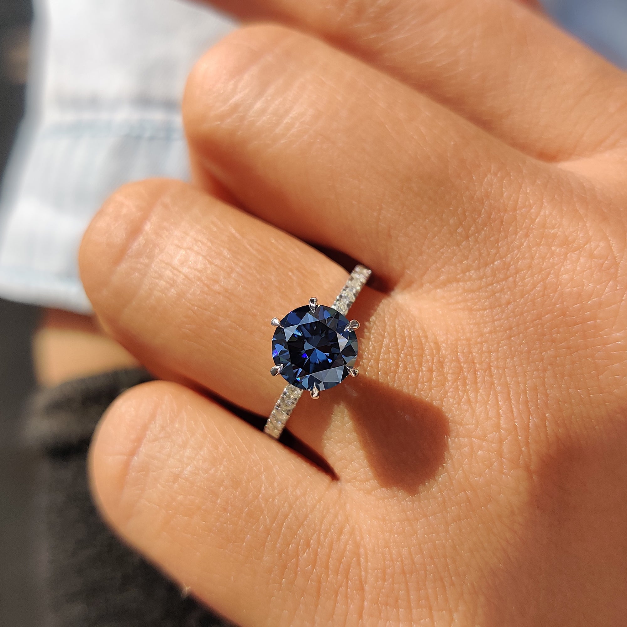 Unique engagement ring with a royal dark blue Moissanite in a white gold pave setting.
