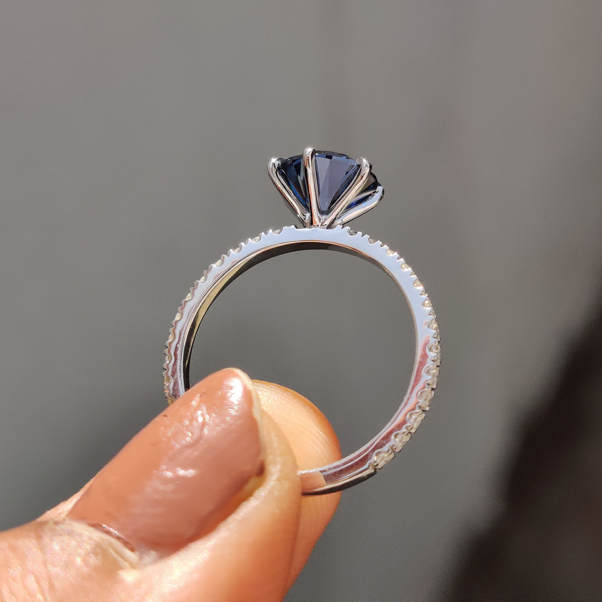 Women’s anniversary ring featuring royal dark blue Moissanite in a round pave band design.
