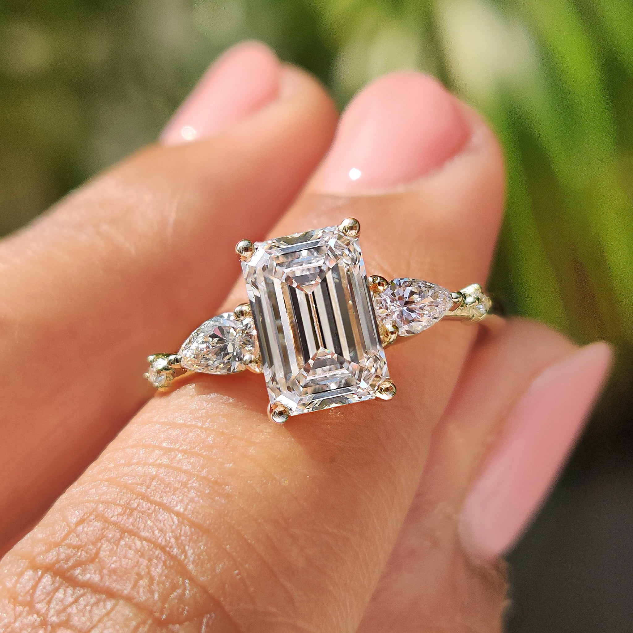 Five stone engagement ring with emerald cut center diamond.
