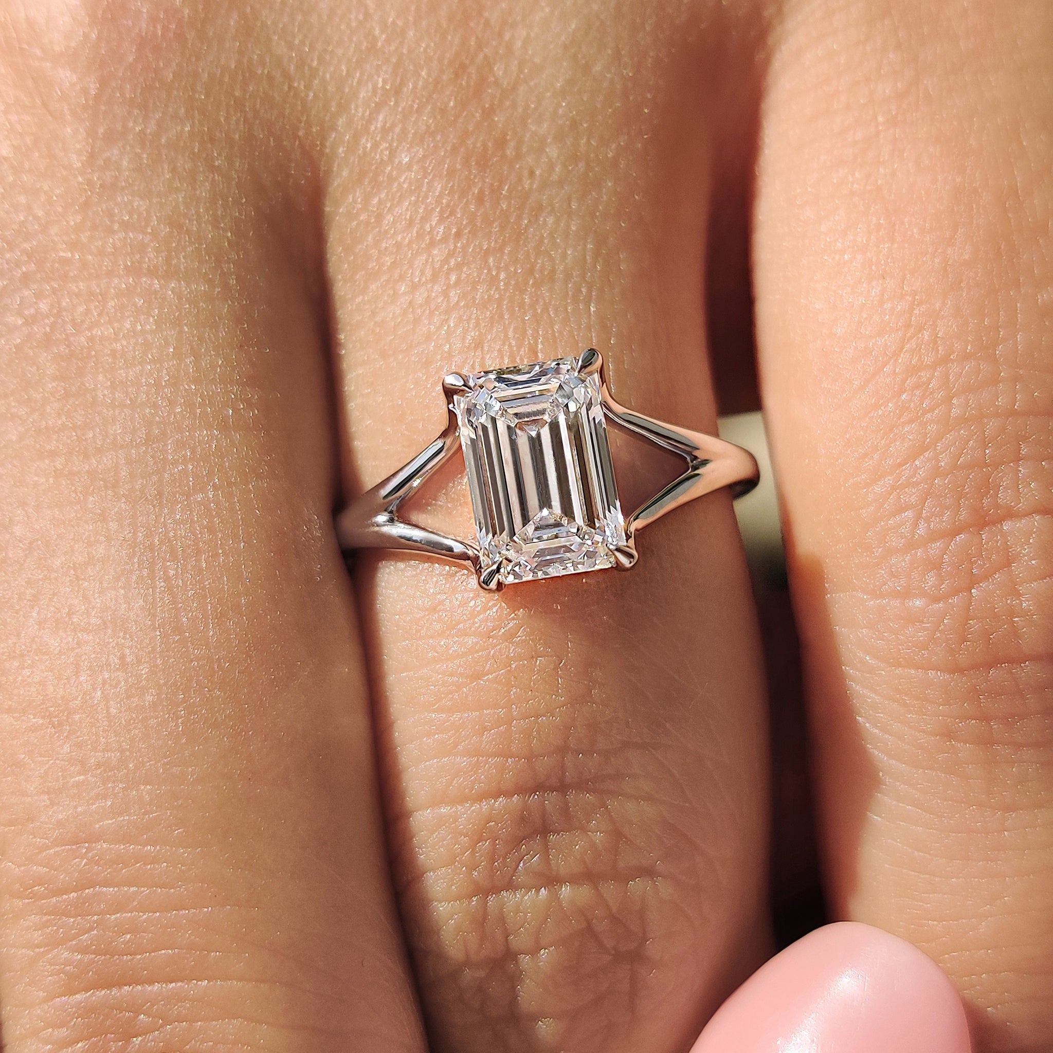Solitaire diamond ring crafted with an emerald cut lab-grown diamond, mounted on a white gold band with an open gallery design.
