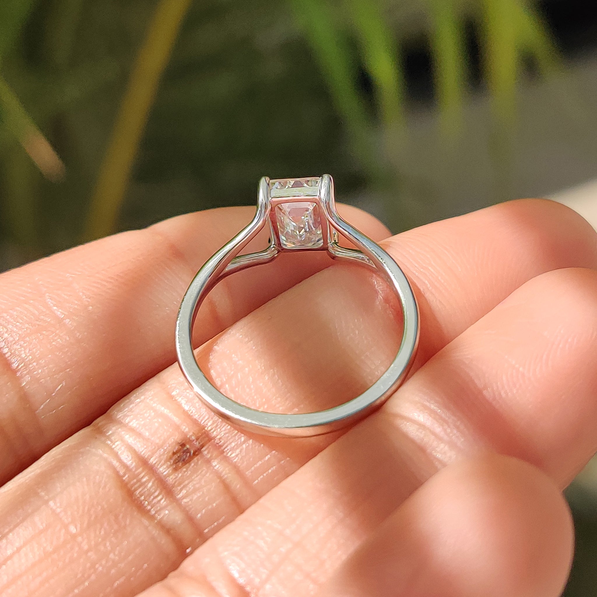 Beautiful handmade jewelry featuring an emerald cut solitaire diamond, mounted on a white gold ring with an open gallery.
