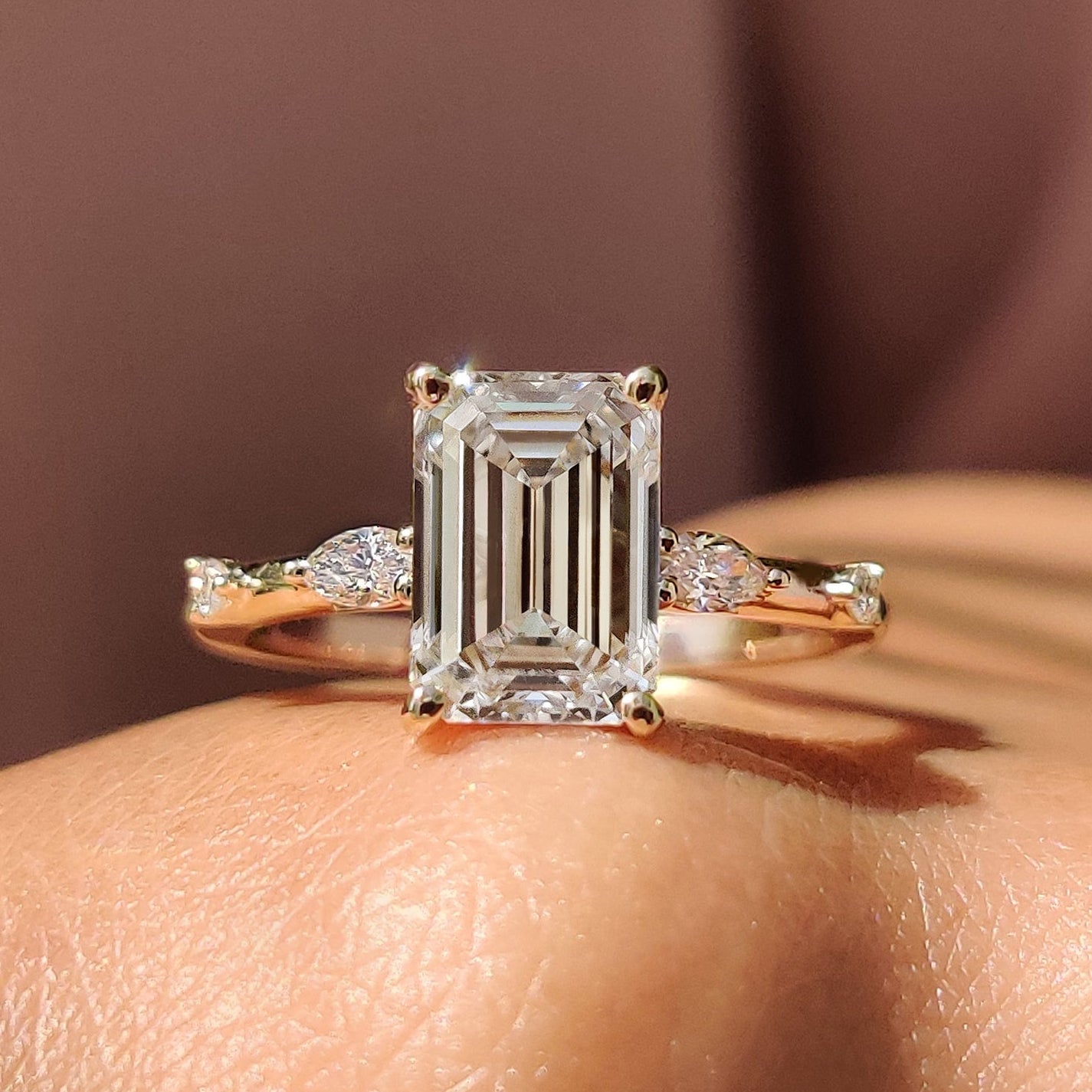 Stone Emerald Cut Diamond Ring set in yellow gold, featuring a marquise and round cut design with a four prong ring setting.
