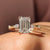 Stone Emerald Cut Diamond Ring set in yellow gold, featuring a marquise and round cut design with a four prong ring setting.
