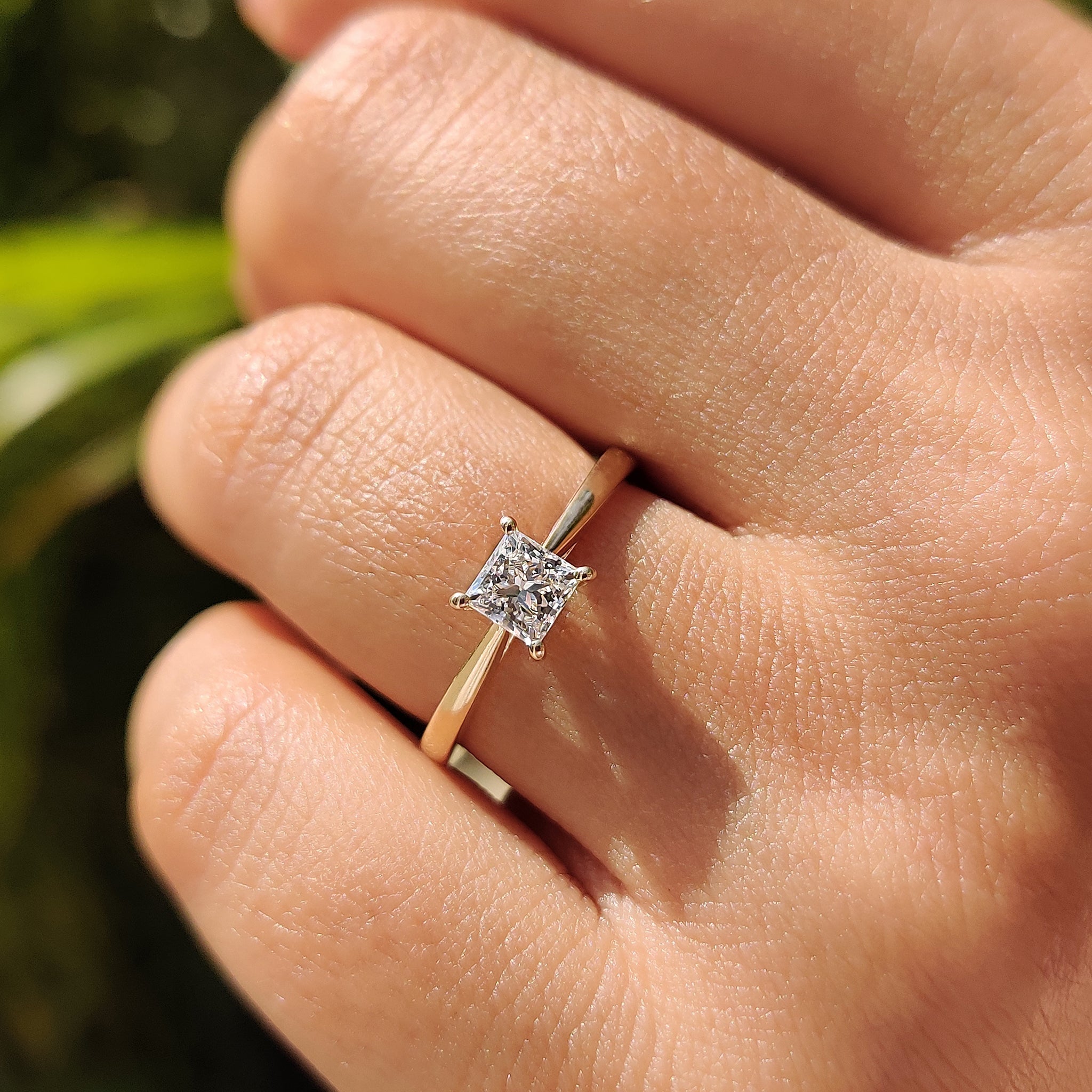 Handmade jewelry featuring a princess cut solitaire diamond ring with a tapered yellow gold band.
