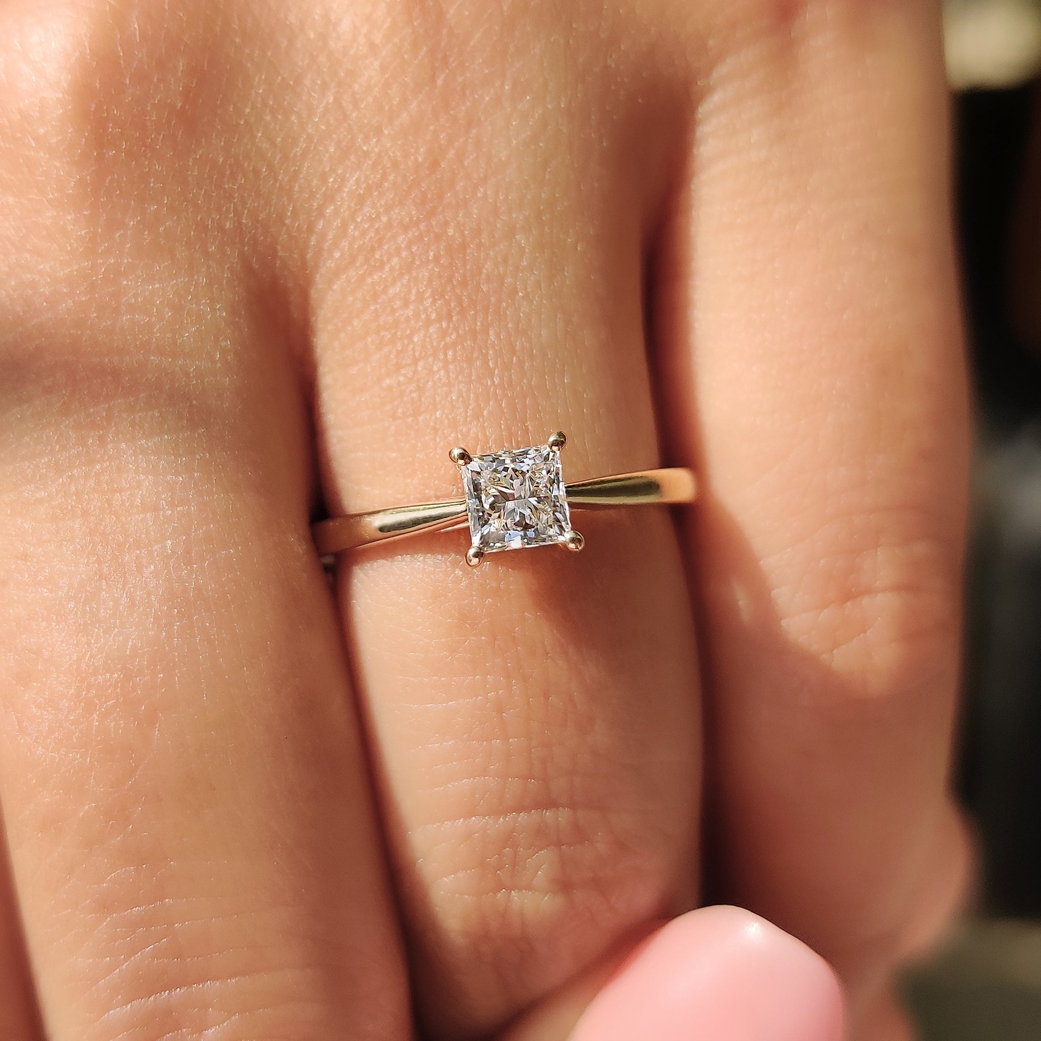 A princess cut solitaire diamond engagement ring set in yellow gold with an elegant cathedral setting.
