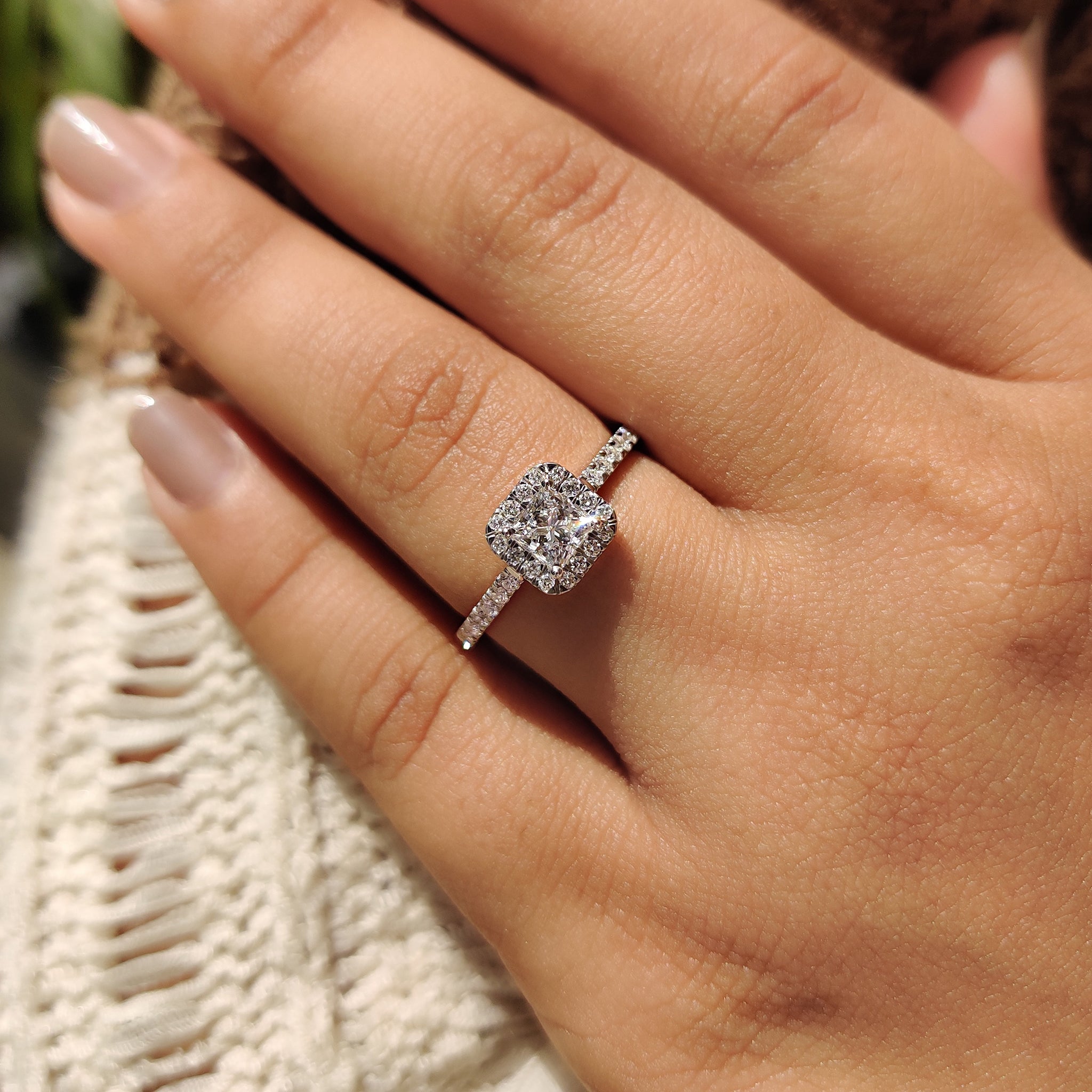 Lab grown diamond halo engagement ring with round cut side stones.
