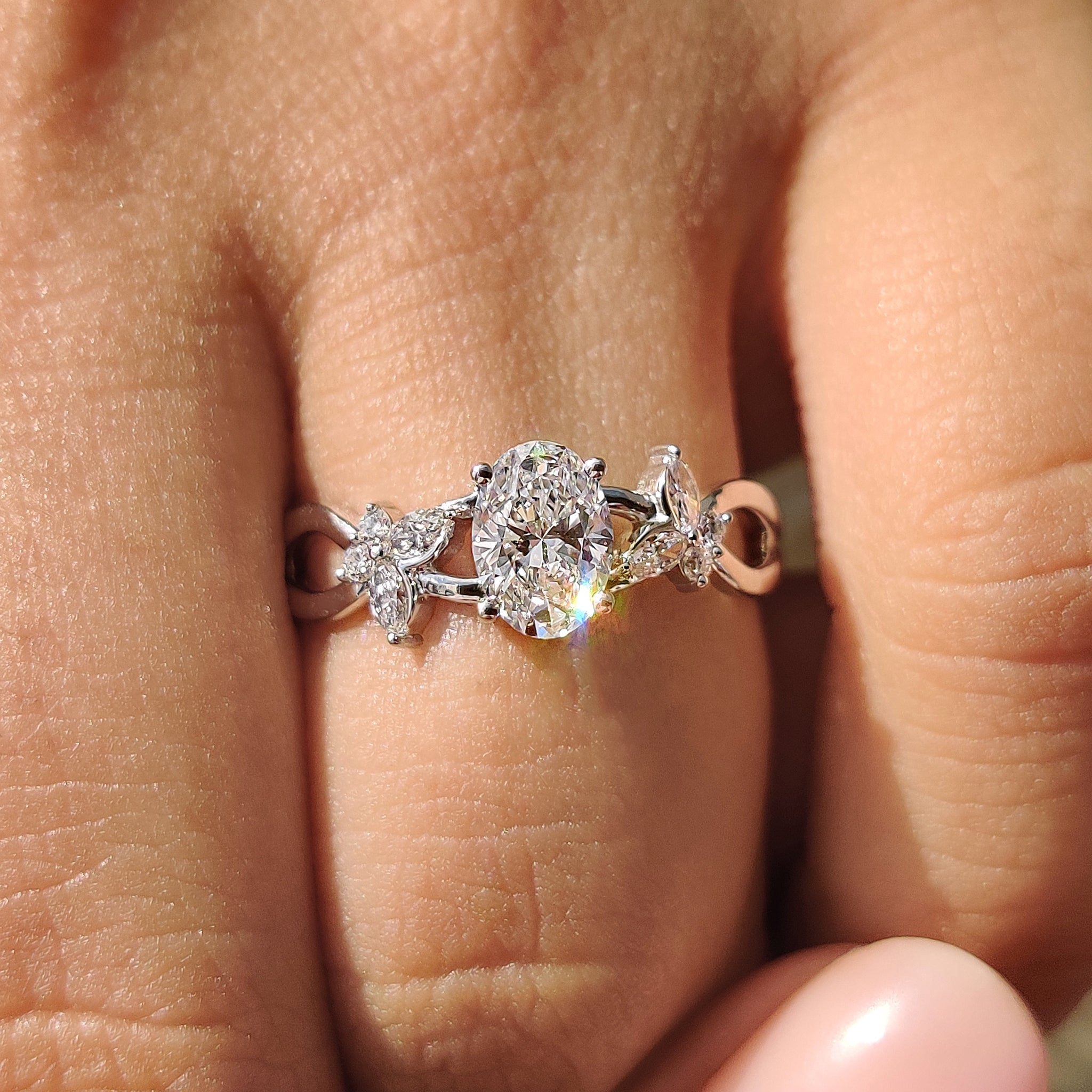 Oval cut engagement ring with marquise and round side stone.