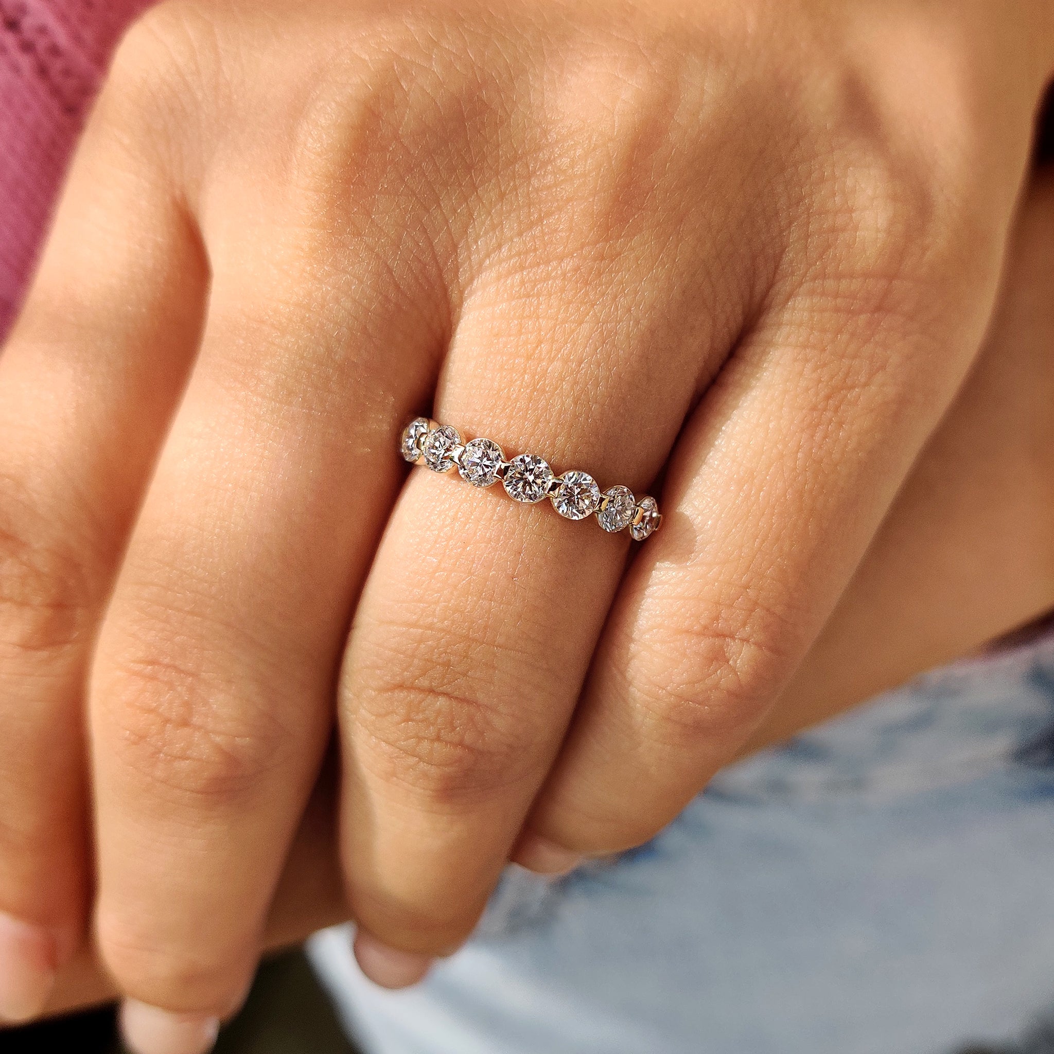 Half eternity diamond band with shared prong design in yellow gold.
