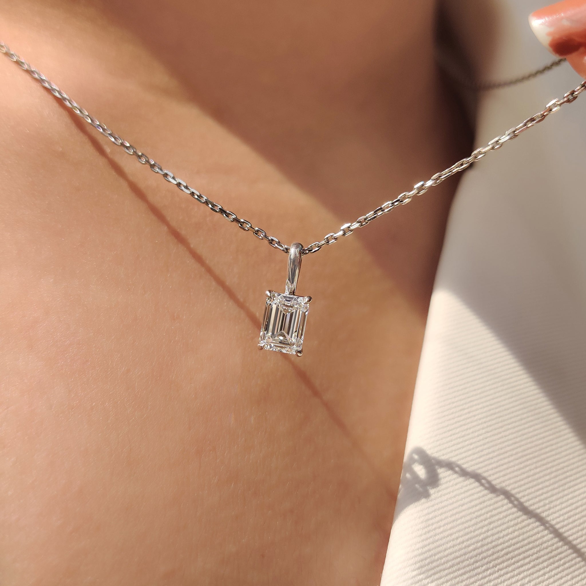 Emerald cut diamond pendant with simple design and four claw prong setting
