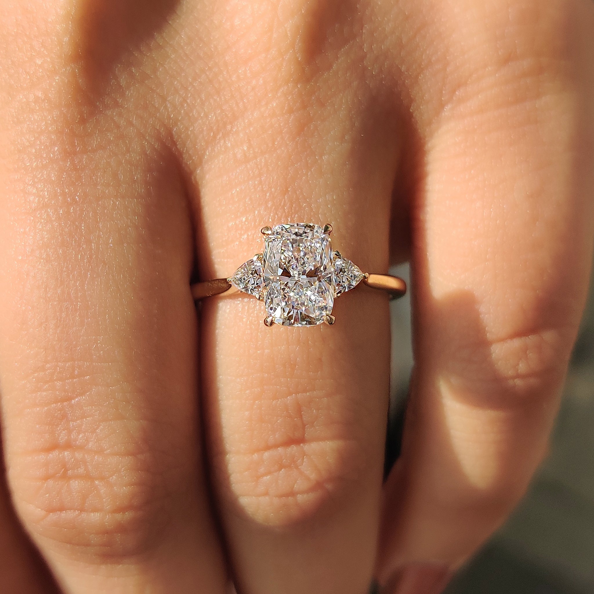 Diamond engagement ring with three stone design and tapered shank in yellow gold.

