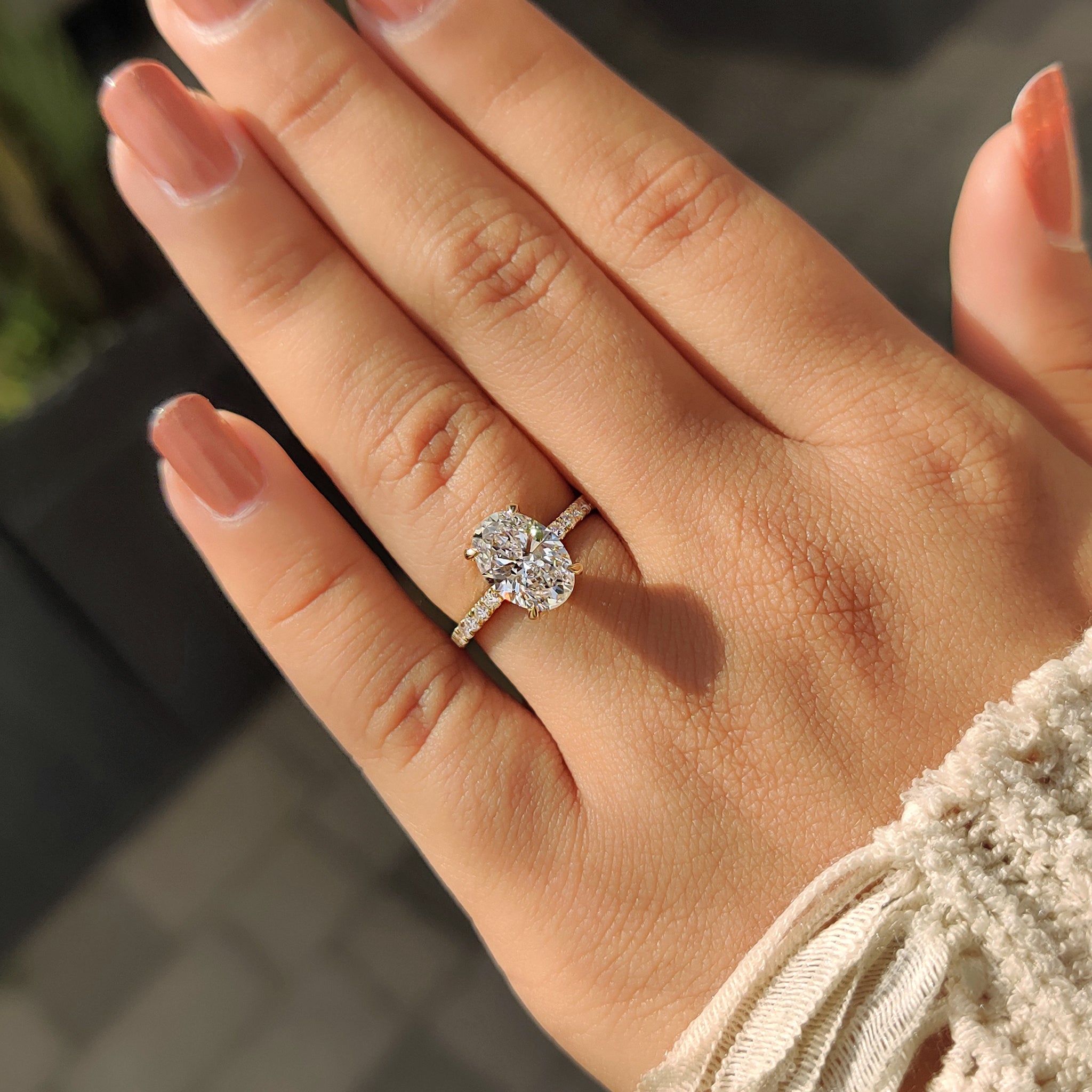 IGI certified oval engagement ring with four claw prong and pave diamonds.