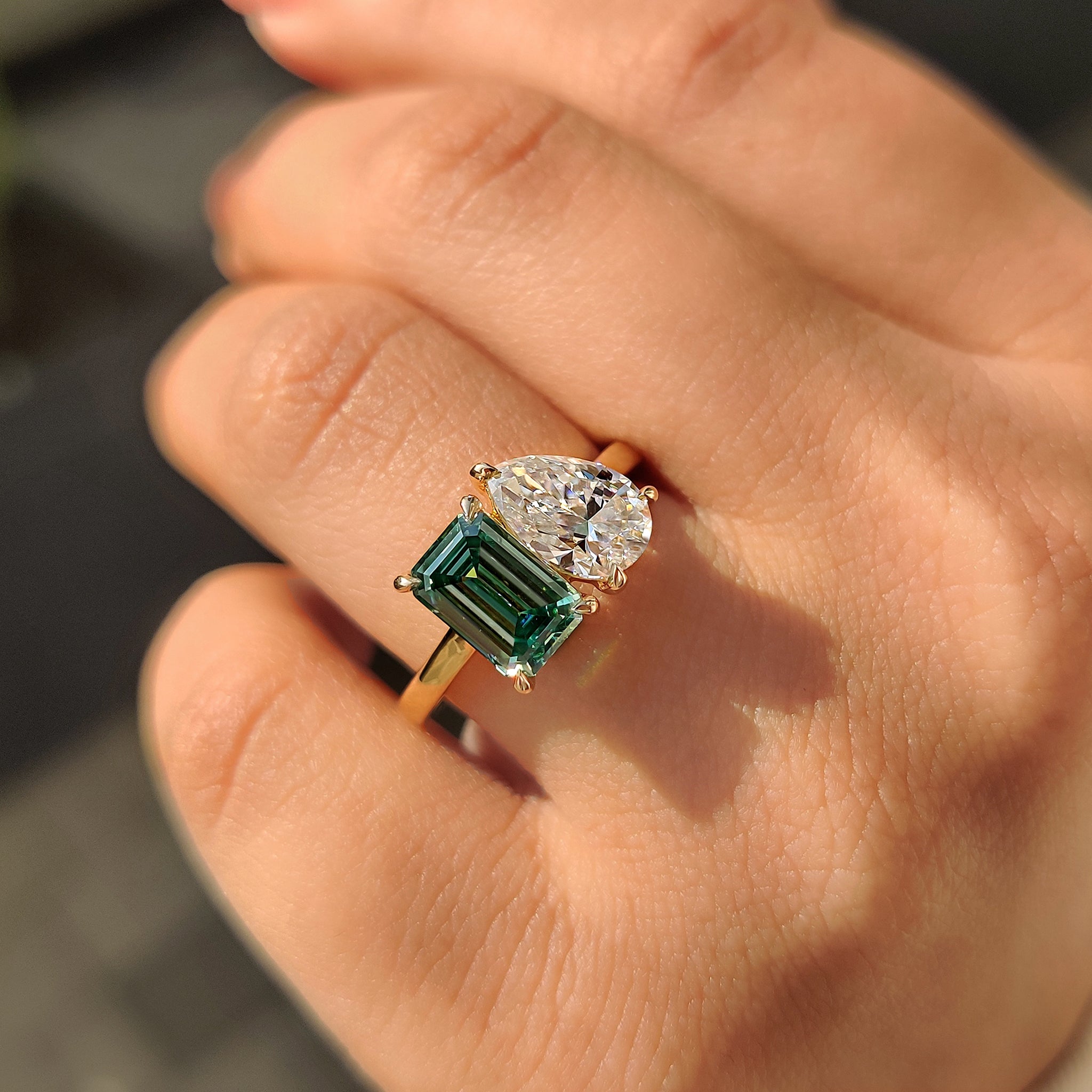 Yellow gold engagement ring with cathedral setting and pear emerald stones.
