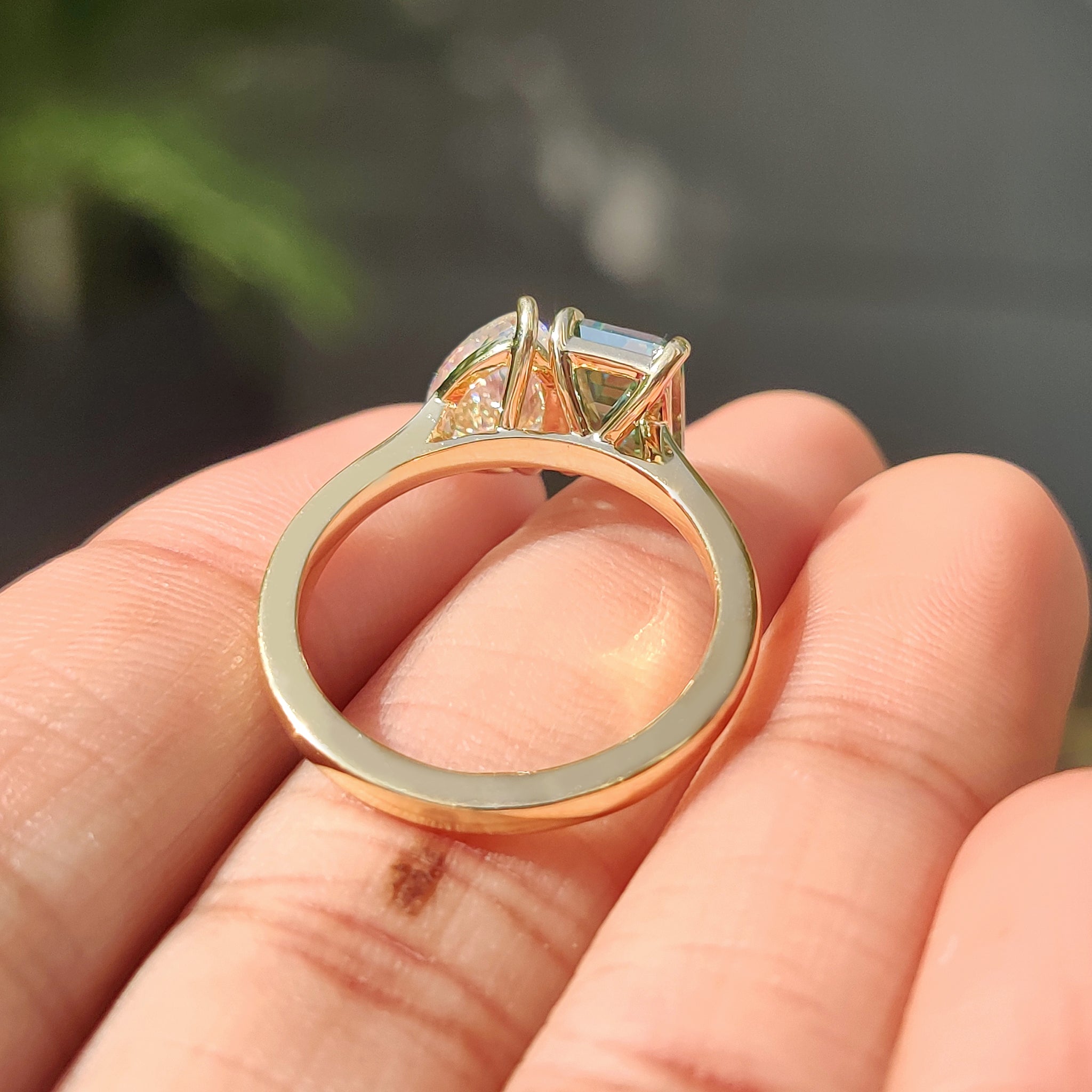 Custom engagement ring with pear and emerald cut stones in yellow gold.