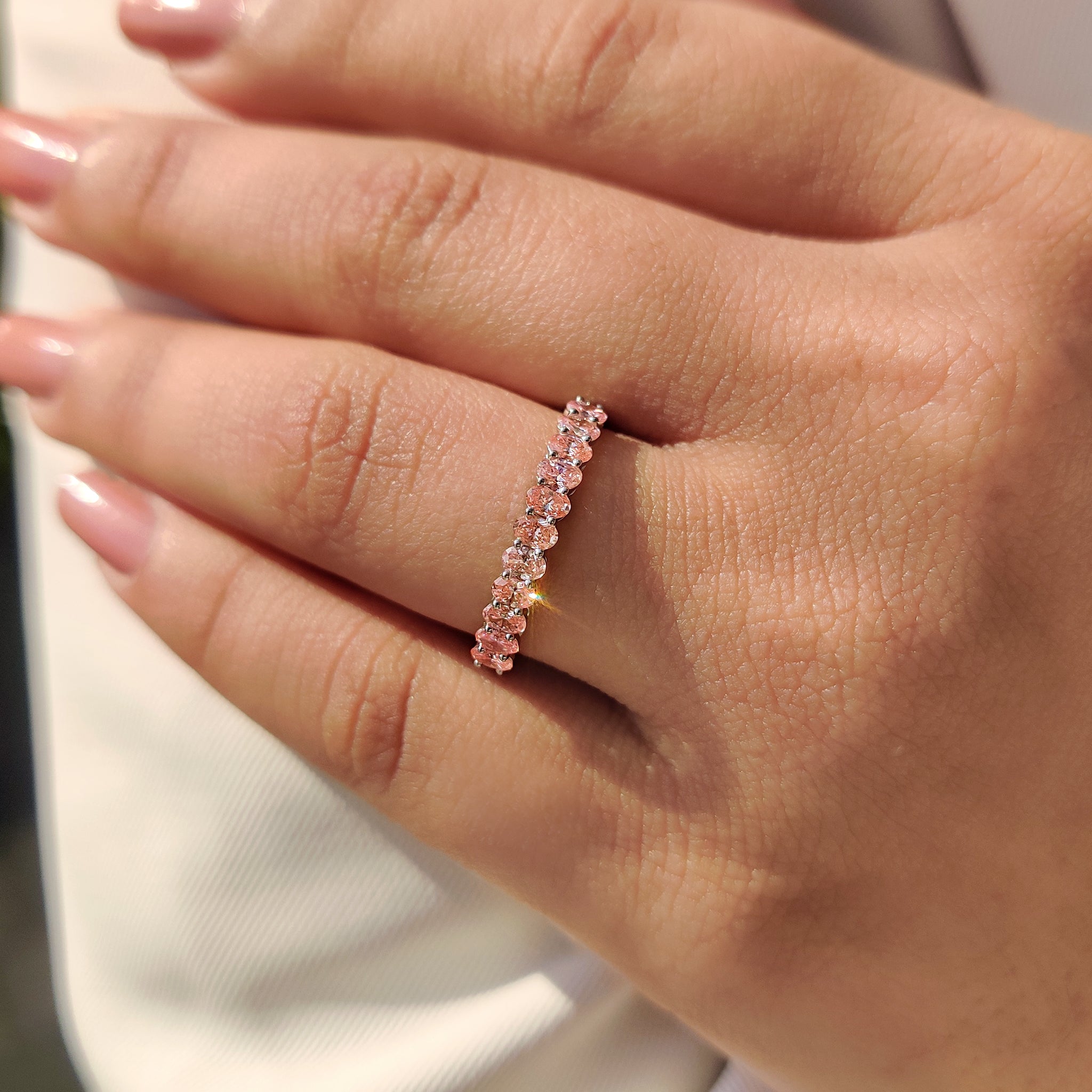 Lab grown pink diamond wedding band with half eternity and shared prong setting.