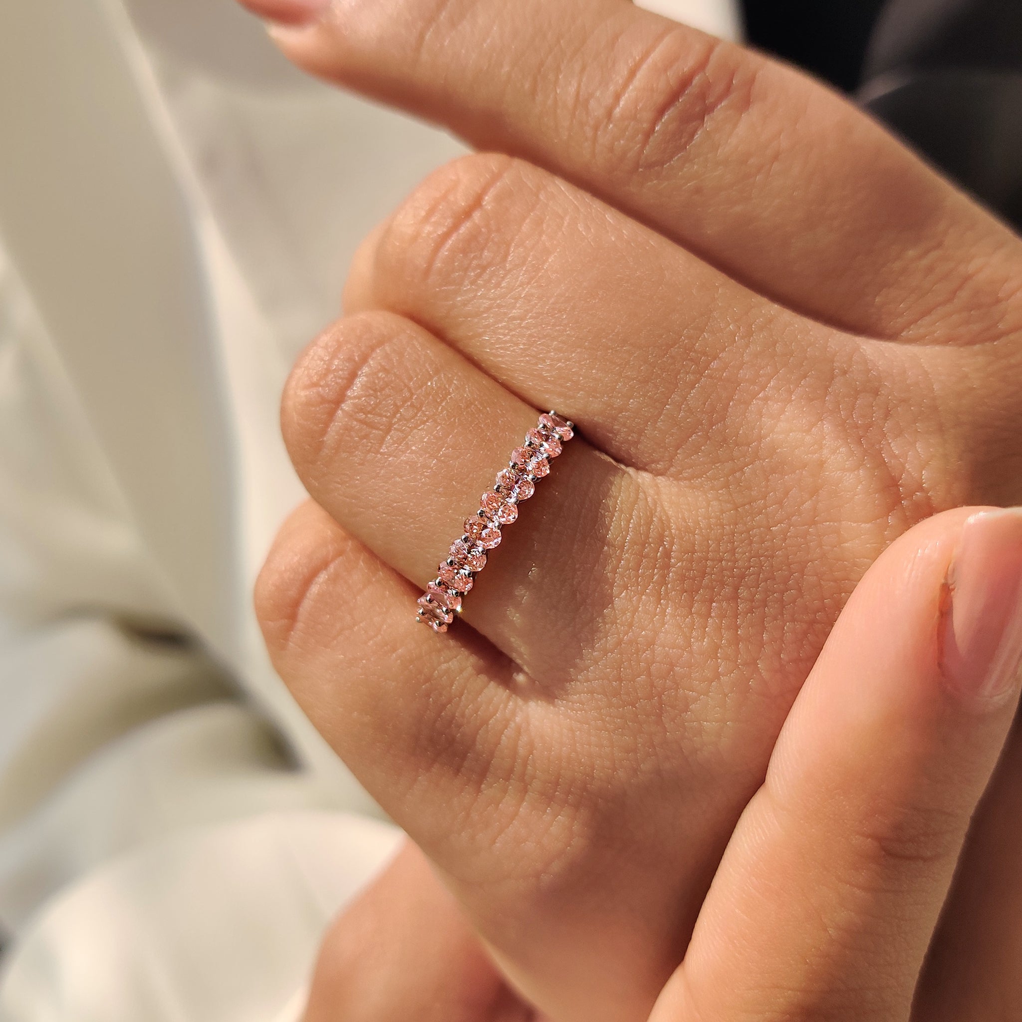 Handmade band with pink oval cut diamond in white gold and half eternity design.