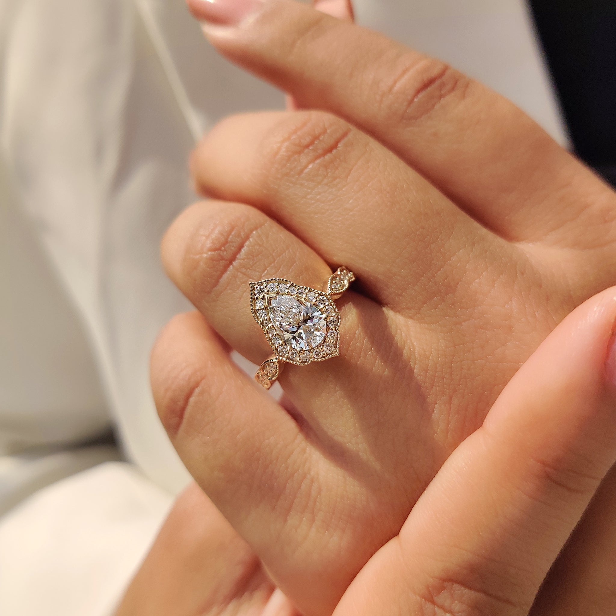 Gold halo ring with round cut halo, marquise cut outline, and pear cut diamond.