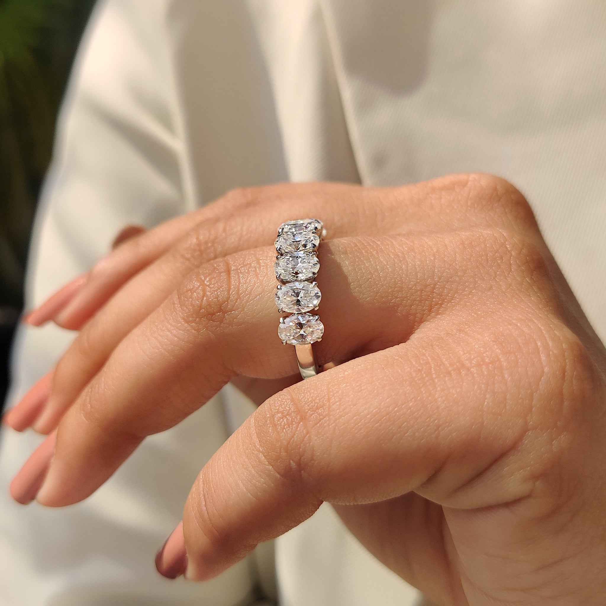 Custom wedding band with oval Moissanite and claw prong setting in white gold.
