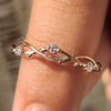 Nature inspired wedding band in rose gold with three stone design and twisted shank.
