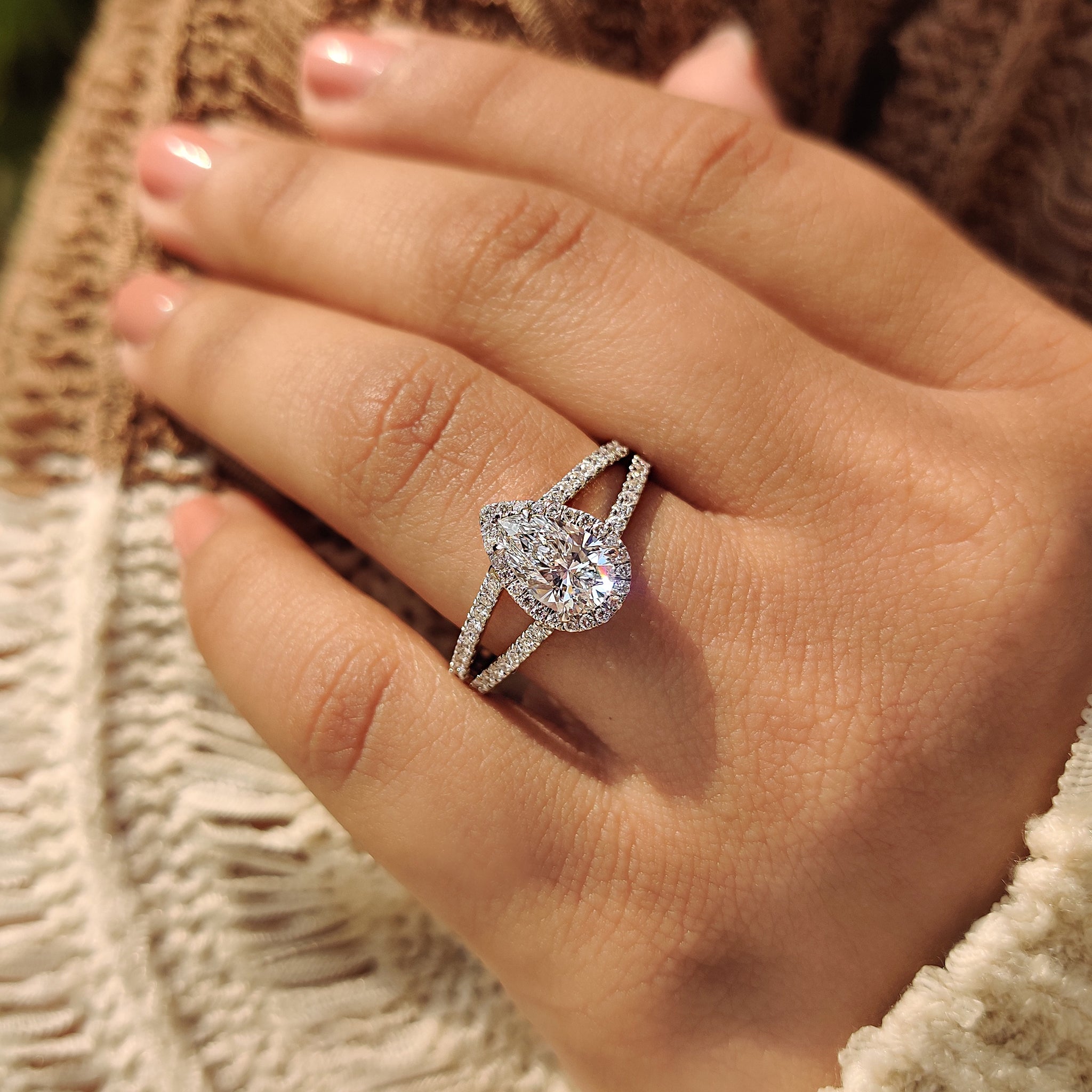 Custom engagement ring with pear cut center, round cut side stones, and split shank band.