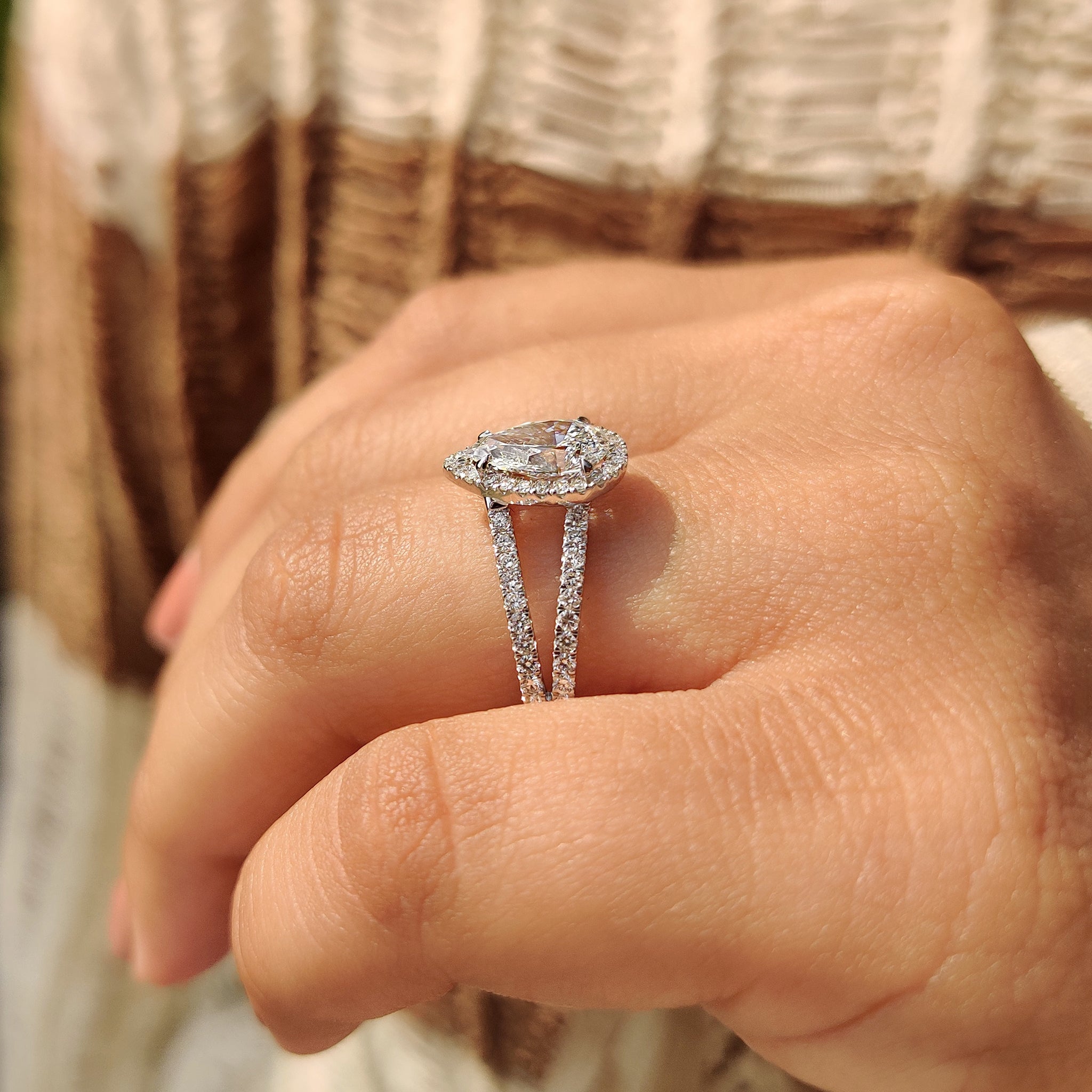 White gold engagement ring with split shank design and pear cut center diamond.