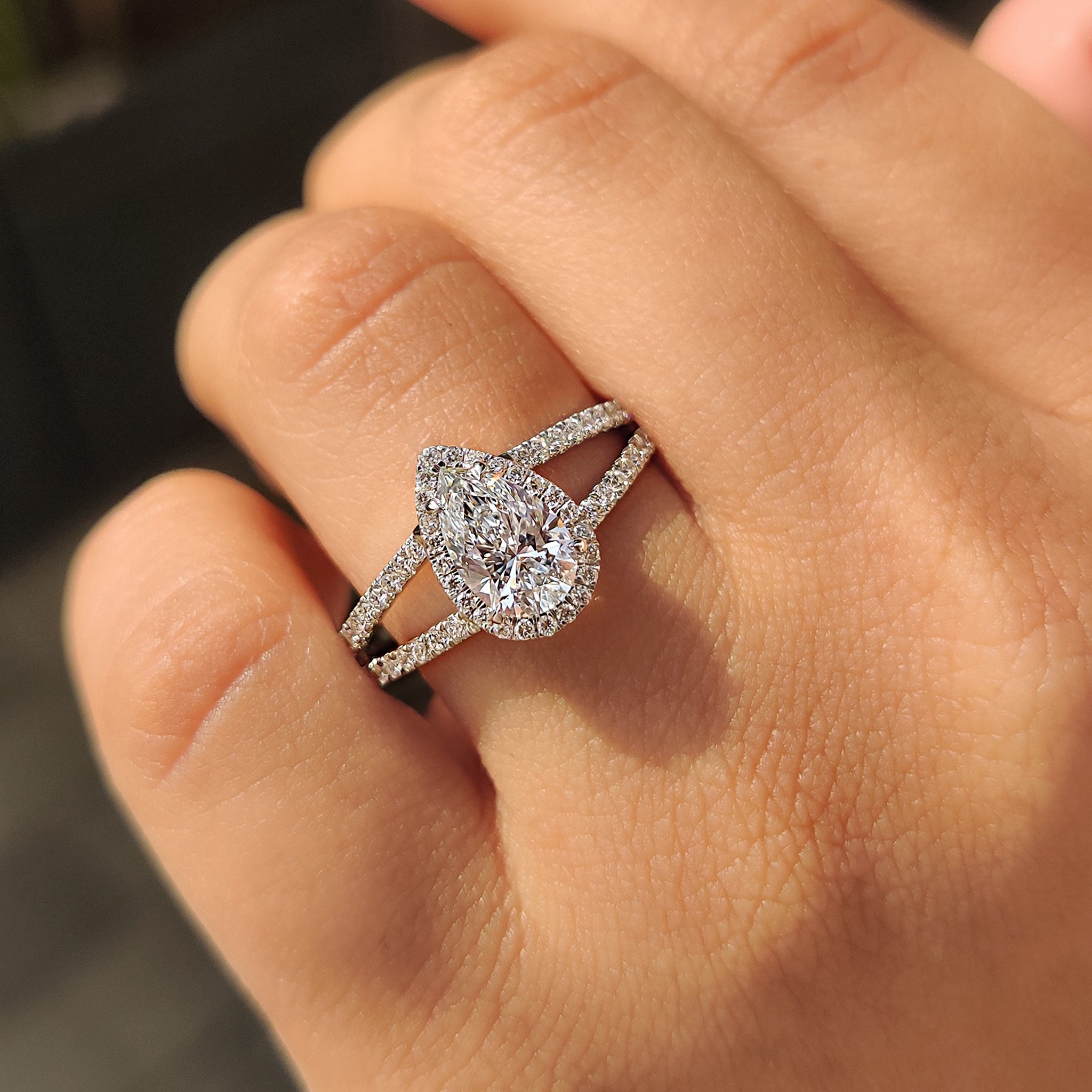 Custom engagement ring with split shank, pear cut center, and halo setting.