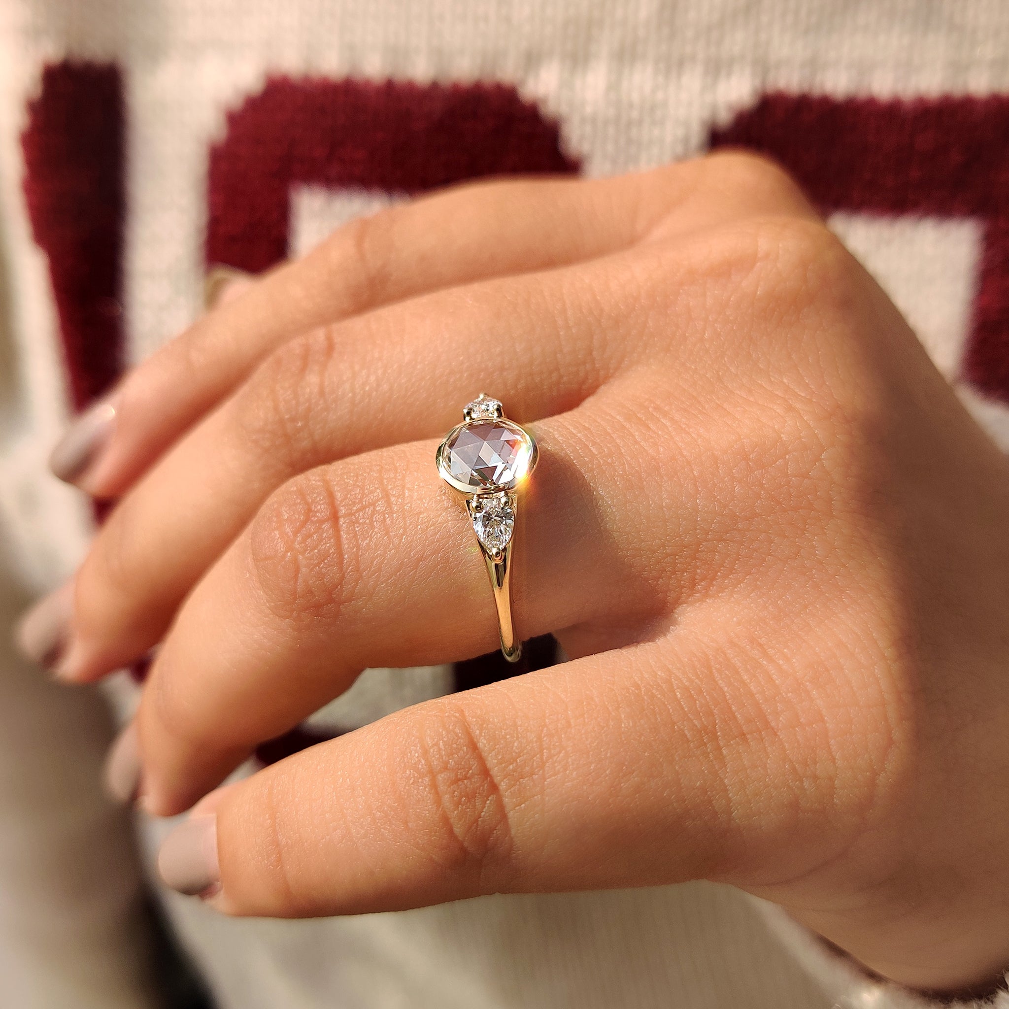 Pear side stone engagement ring with a three stone layout.
