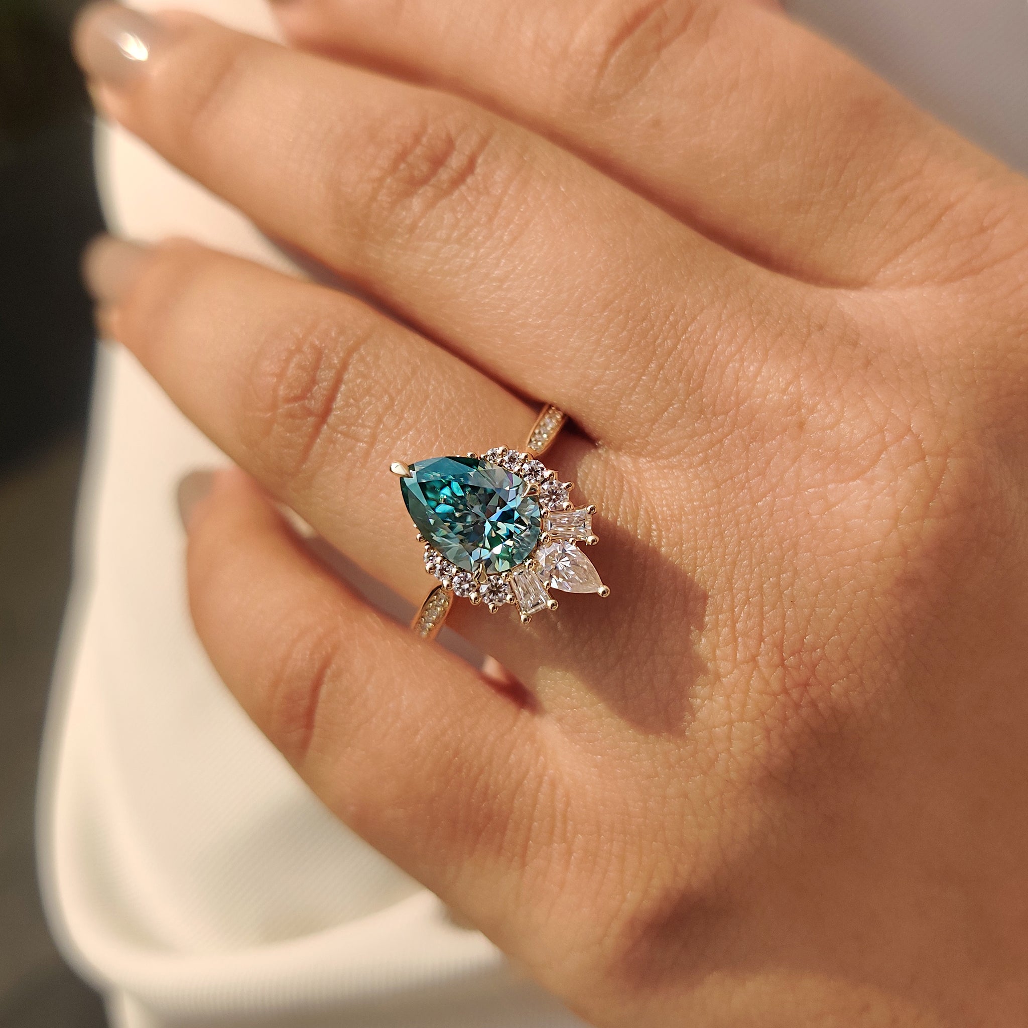 Green pear ring with tapered baguette side stones.
