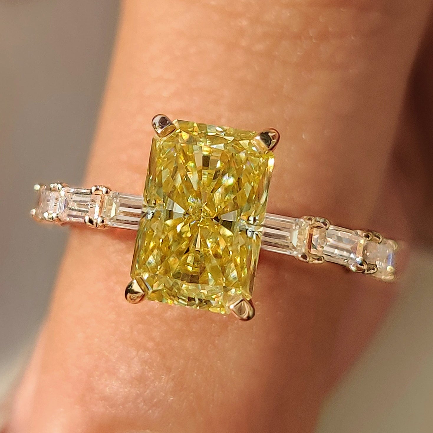 Yellow moissanite ring with radiant cut stone in pave setting.
