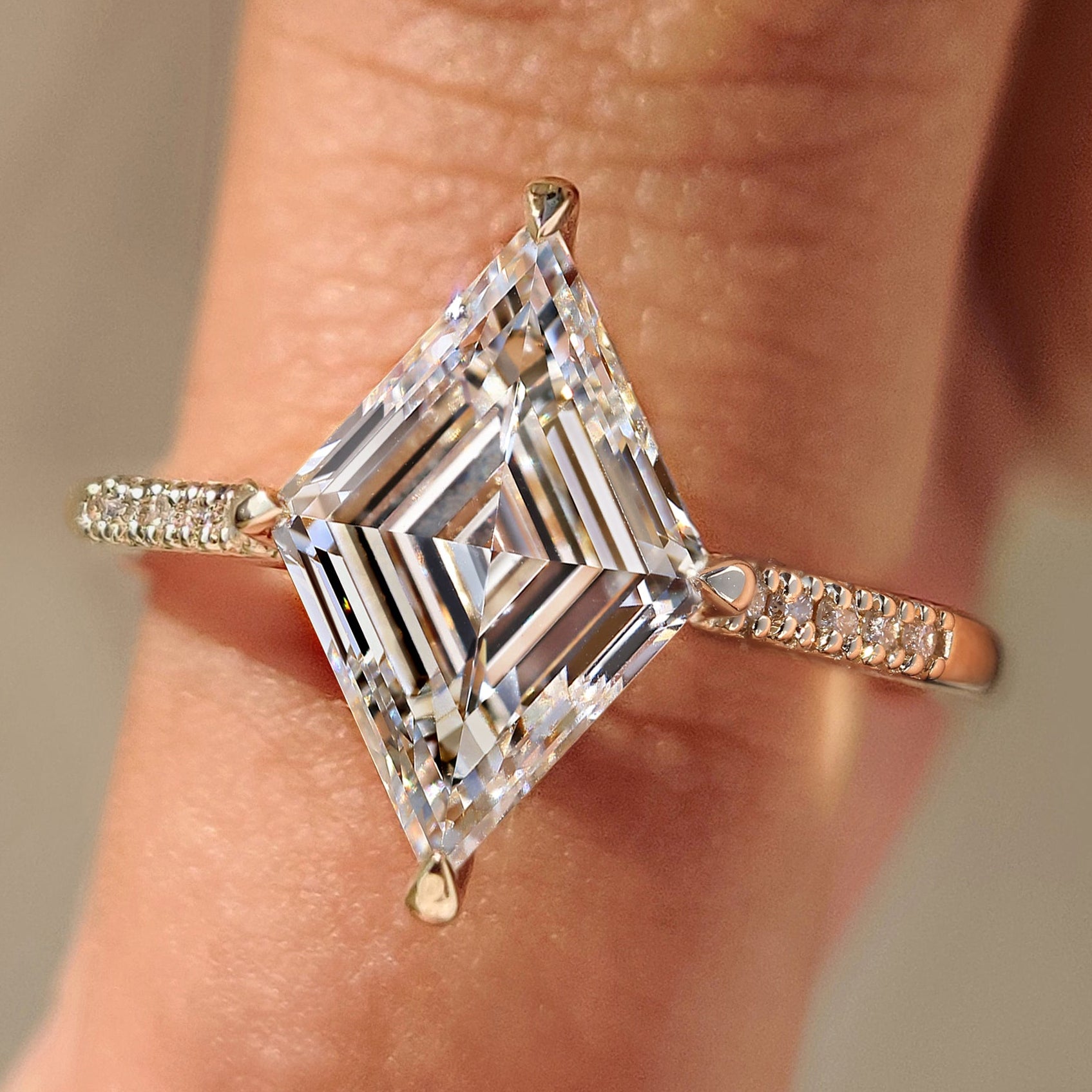 Lozenge cut diamond ring with pave band and round diamonds.

