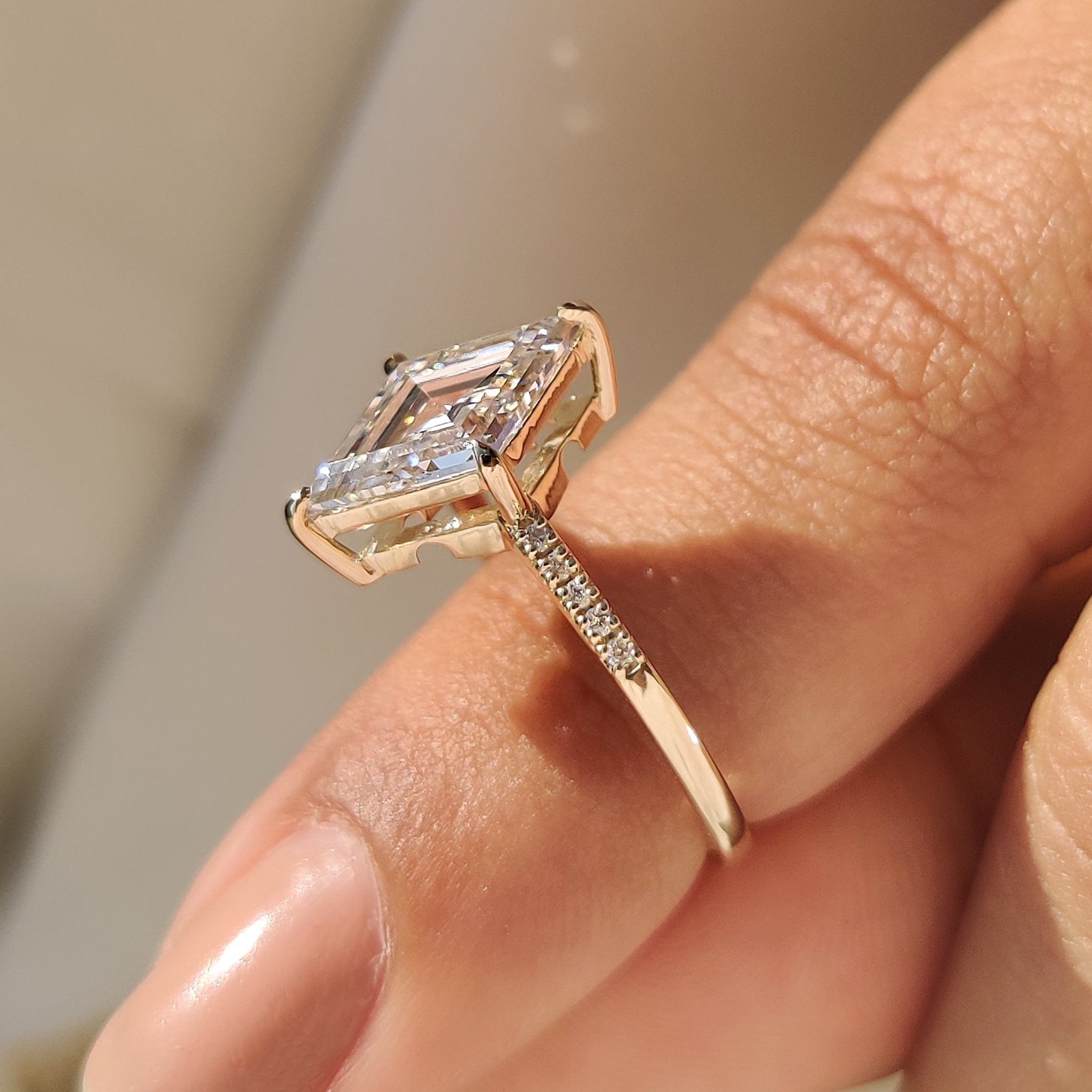 Carat Diamonds lozenge cut diamond ring with pave band.

