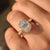 Emerald cut ring with round diamond halo and cathedral setting.
