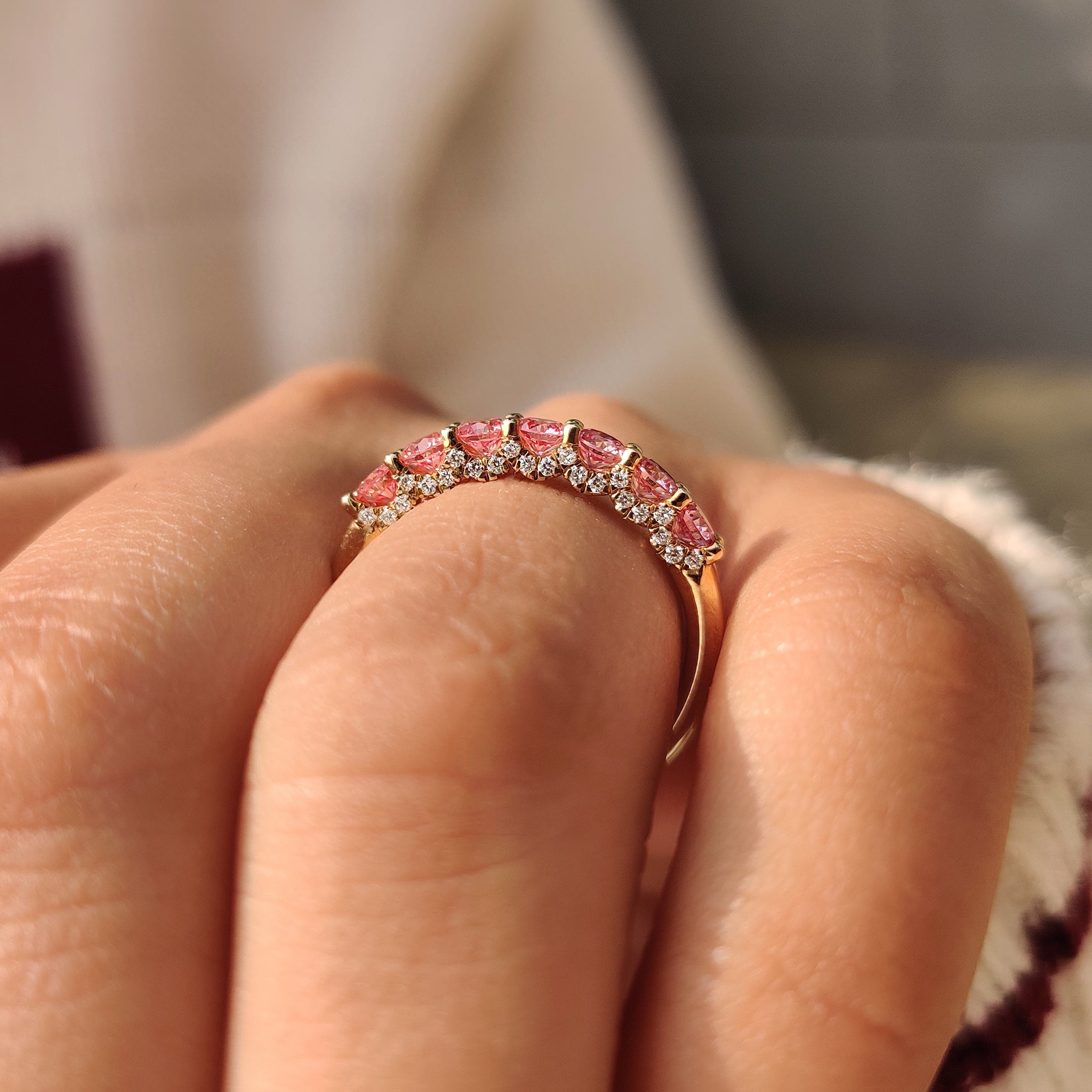 Tapered shank round diamond band with pink stones.
