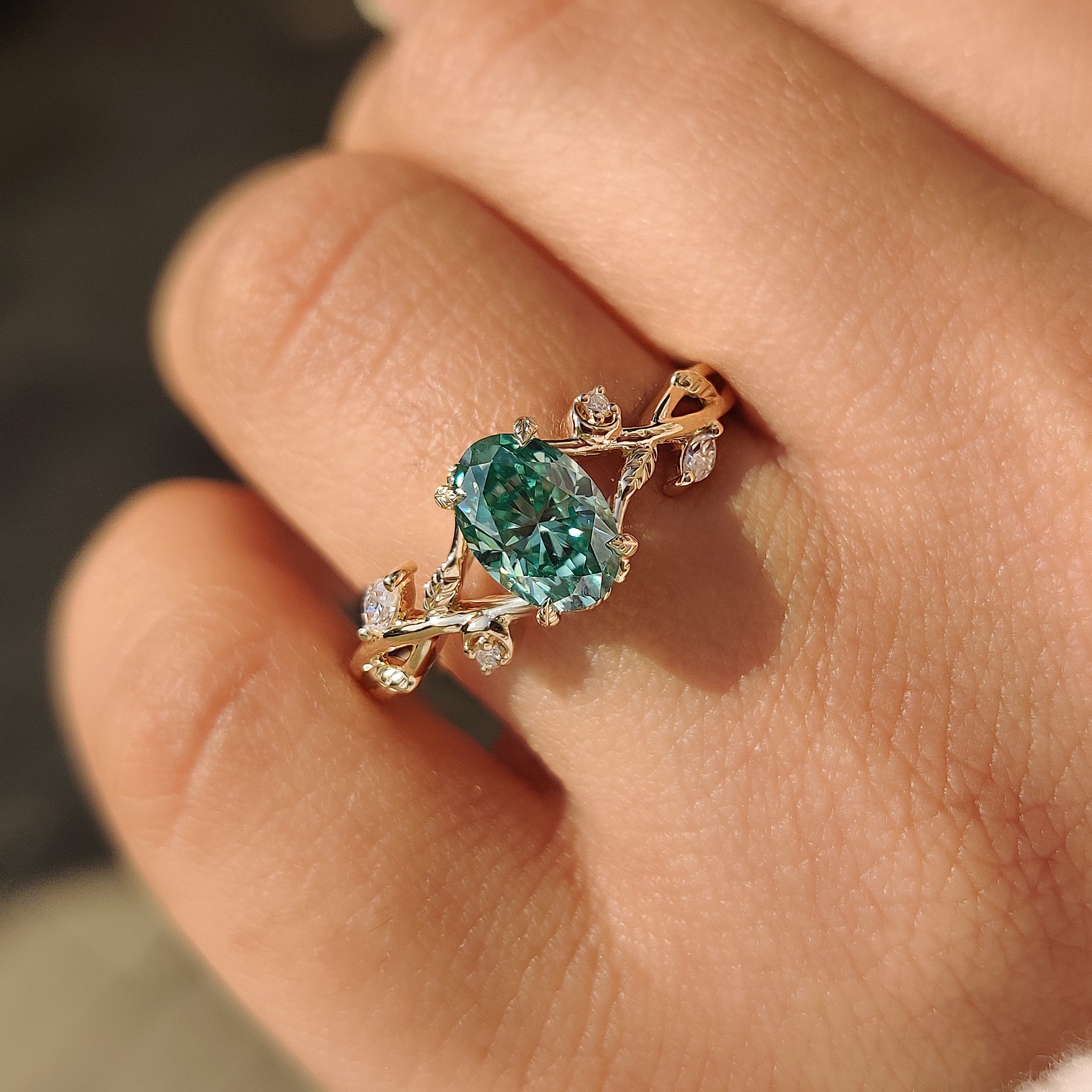 Green moissanite ring with nature inspired five stone setting.
