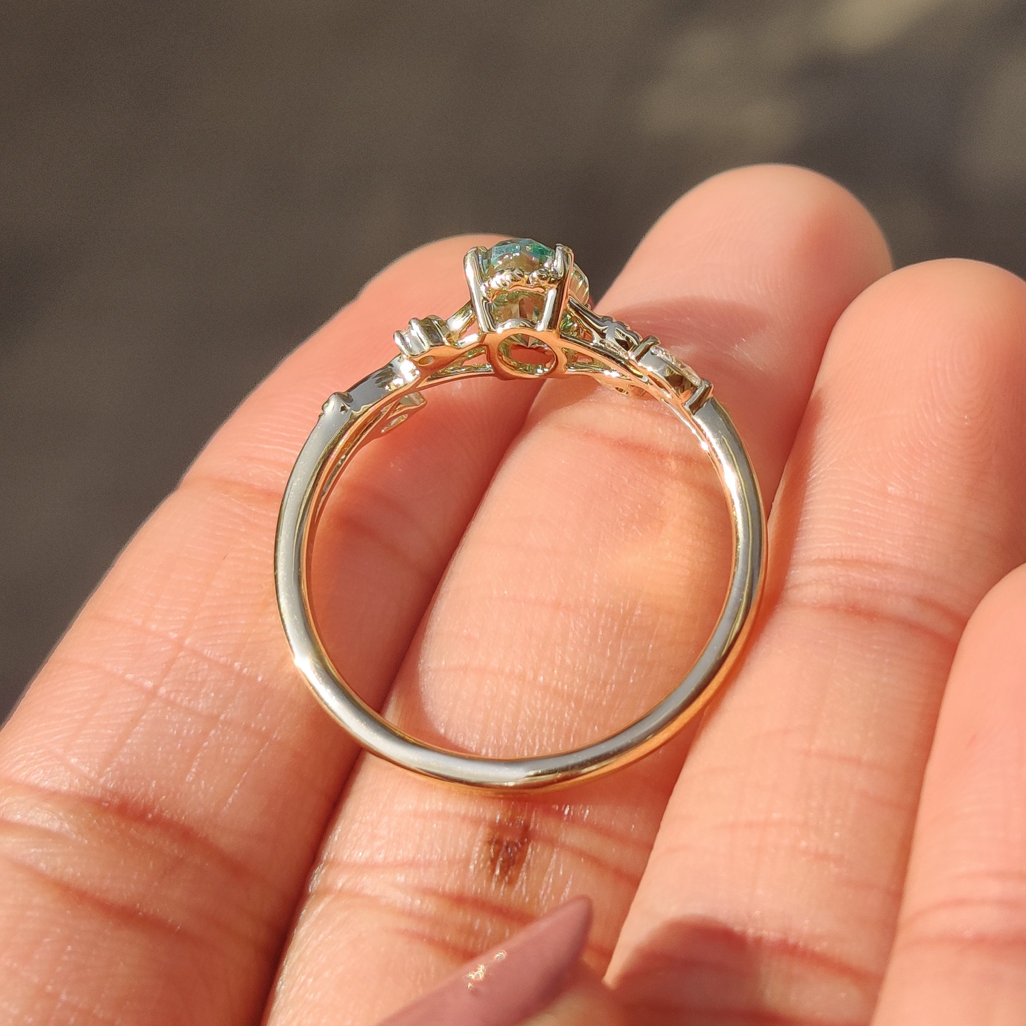 Oval cut green moissanite ring with elegant leaf prongs.
