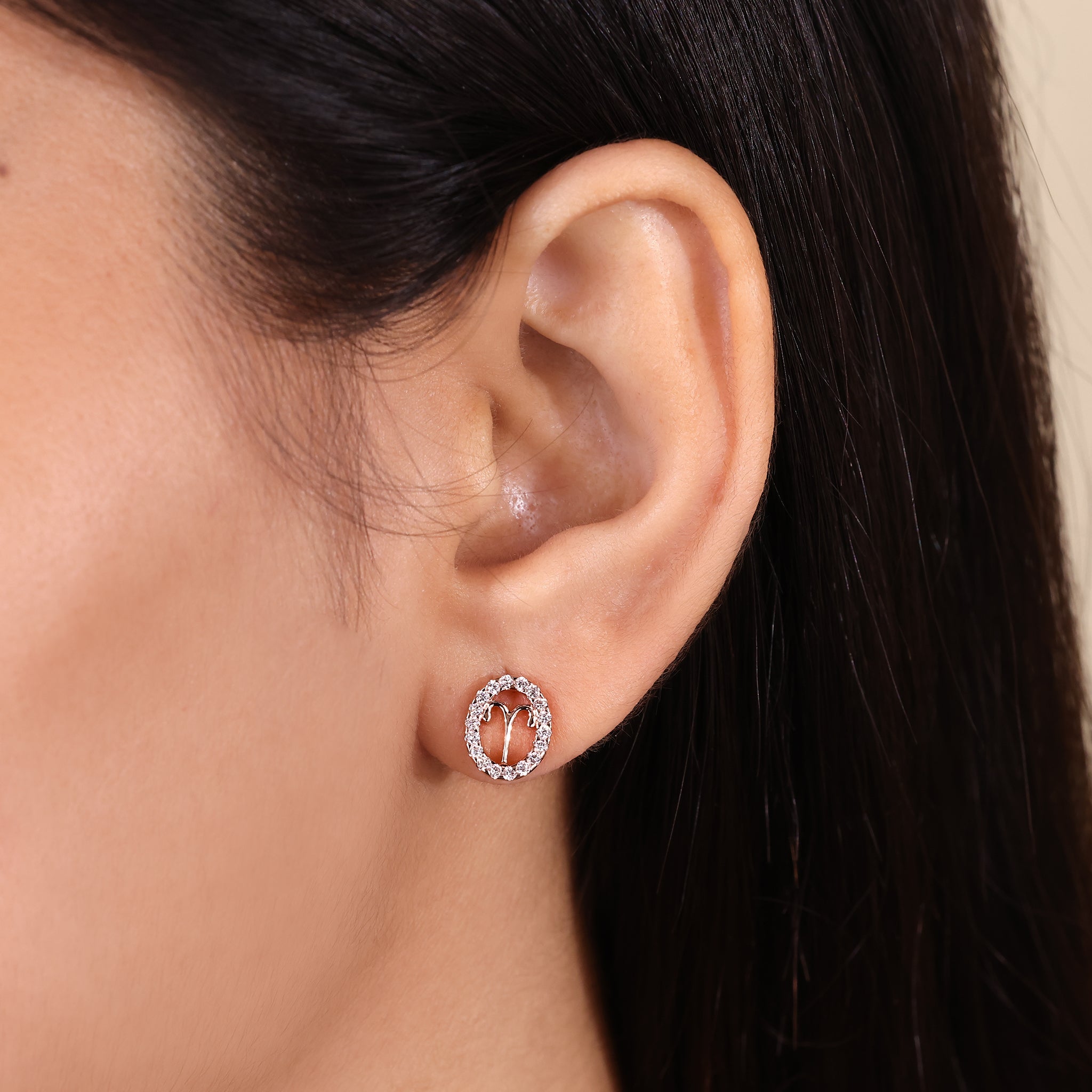 Custom Aries zodiac earrings in rose gold with halo diamonds.
