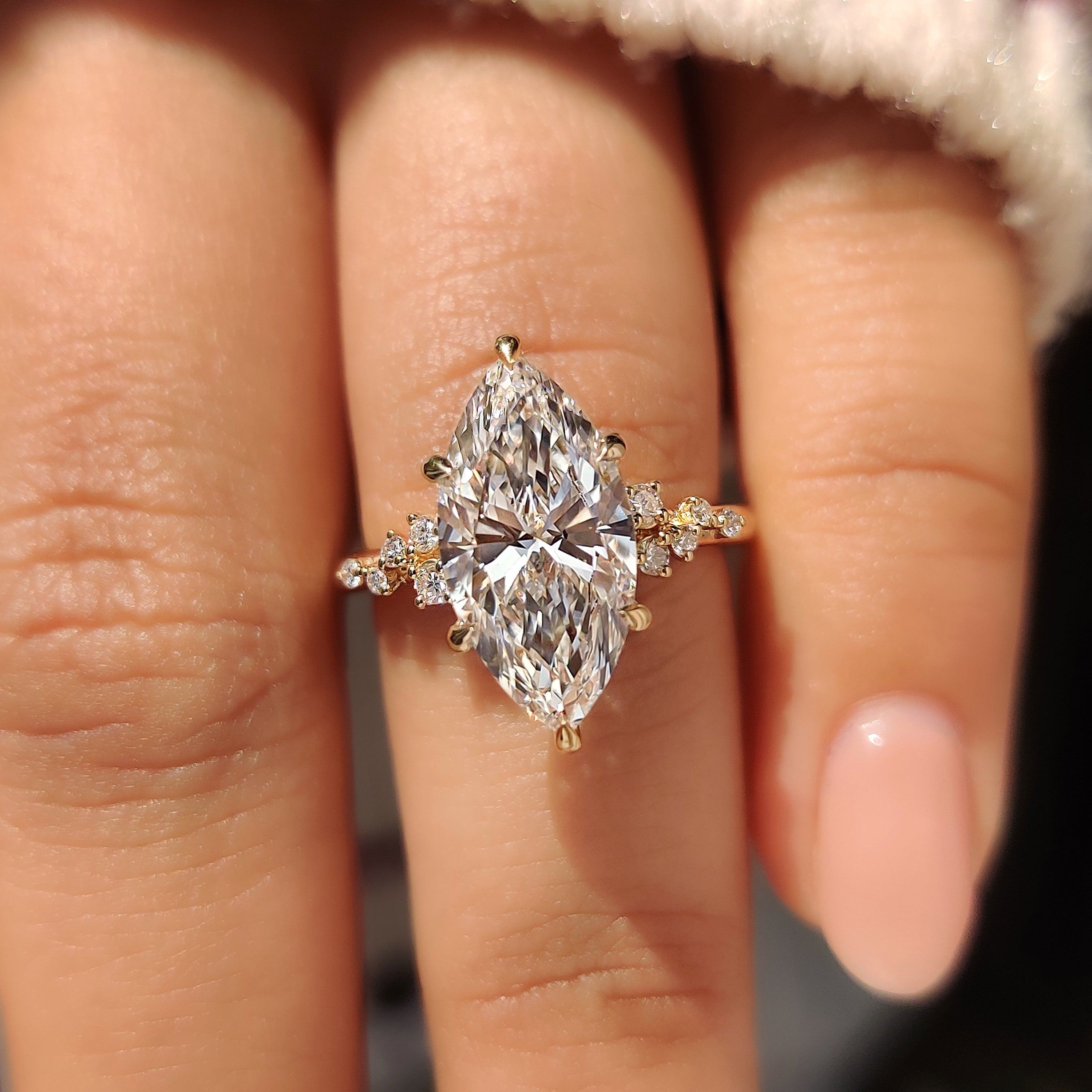 Marquise cut engagement ring crafted with round stones and cluster setting.
