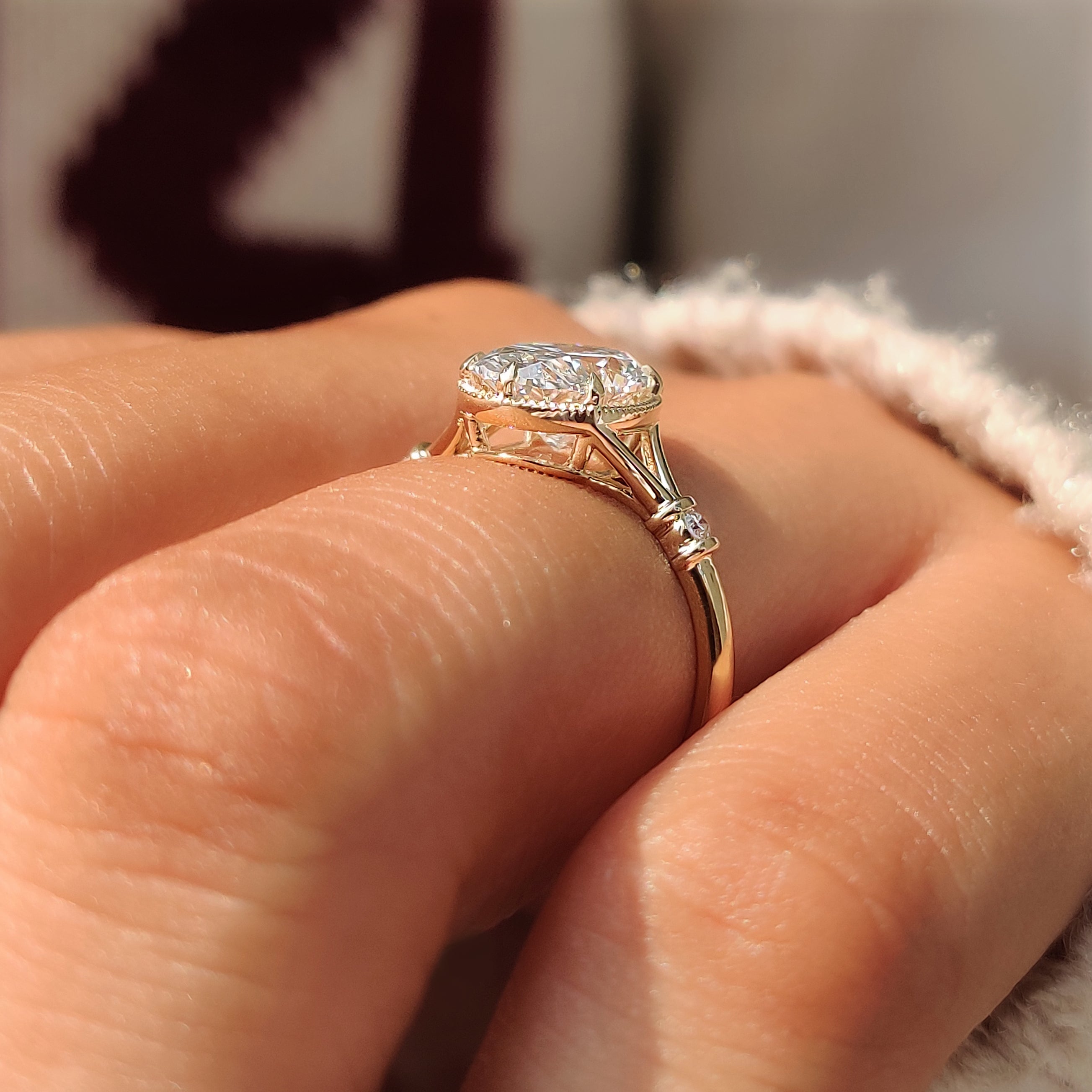 Oval center diamond with round side stones in a three stone setting.
