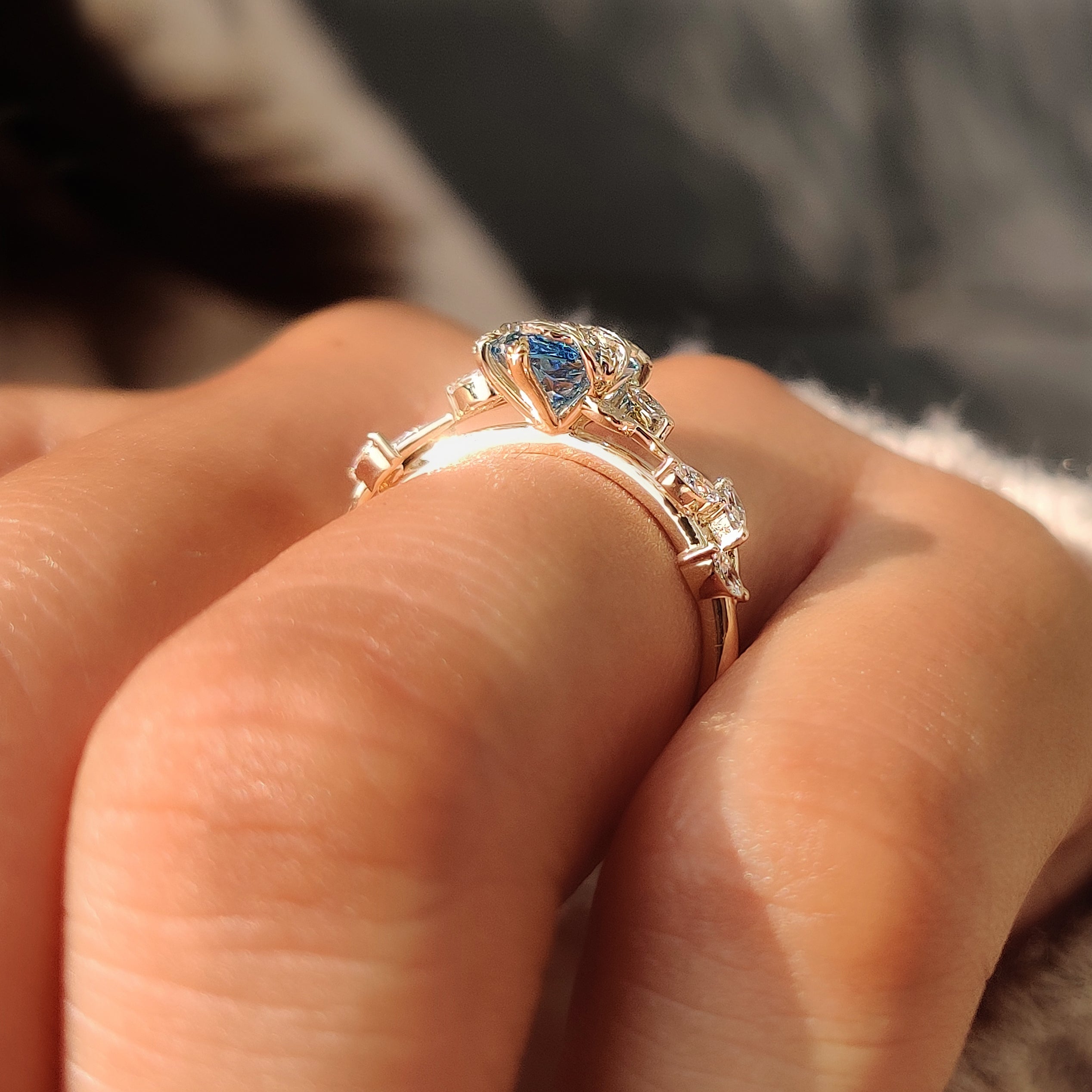 Blue center diamond with marquise side stones in yellow gold.
