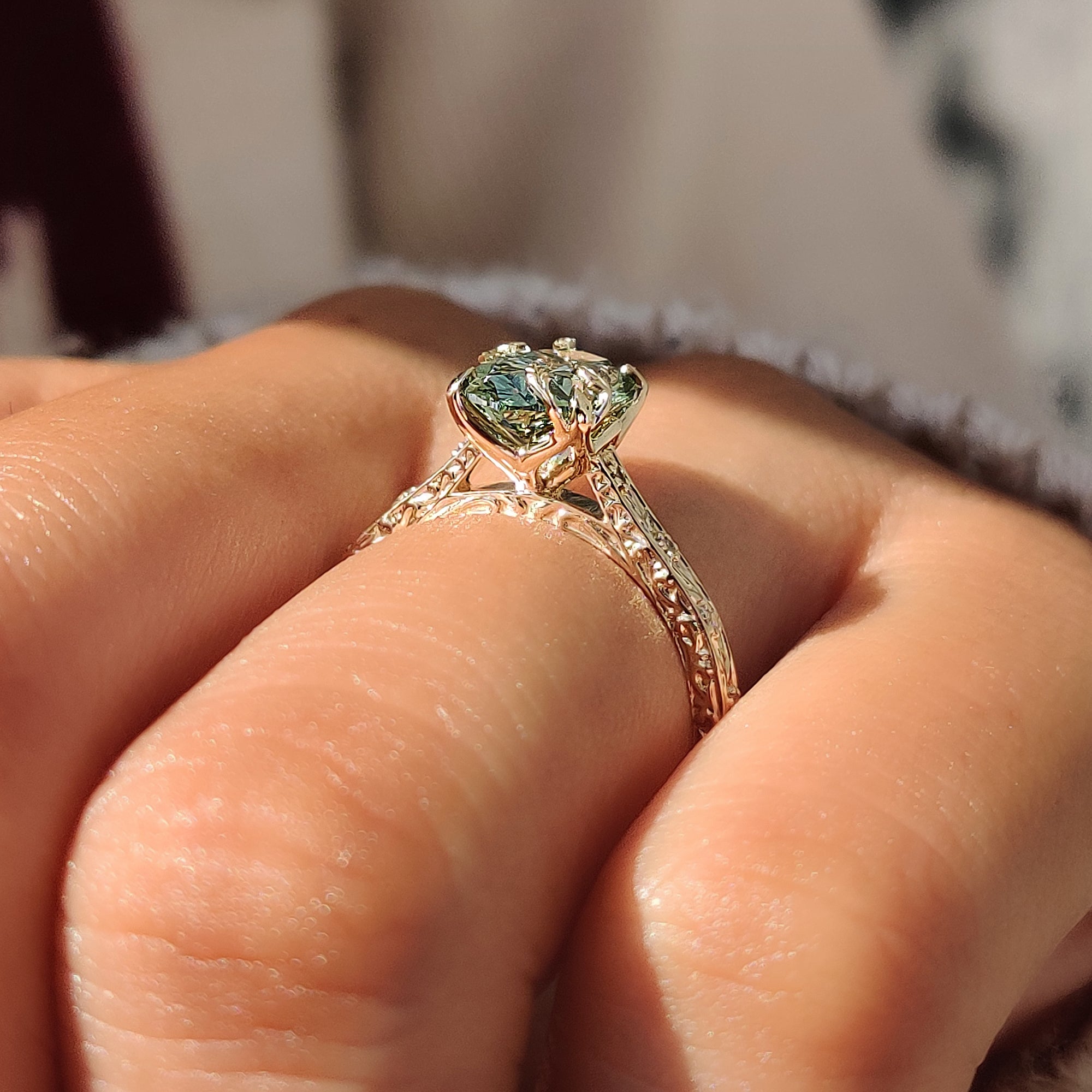 Four claw prongs securing the green oval center diamond.
