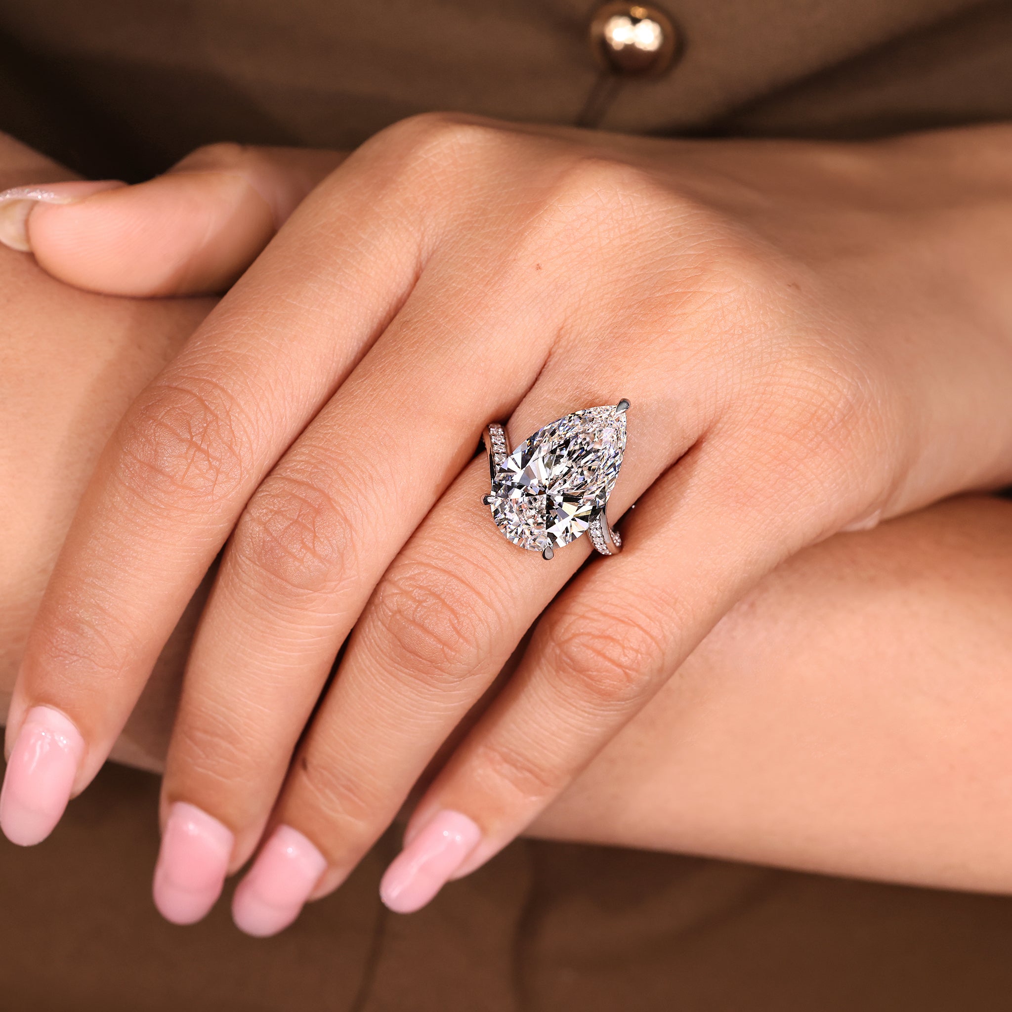 Lab grown pear diamond centerpiece surrounded by double row round pave accents.
