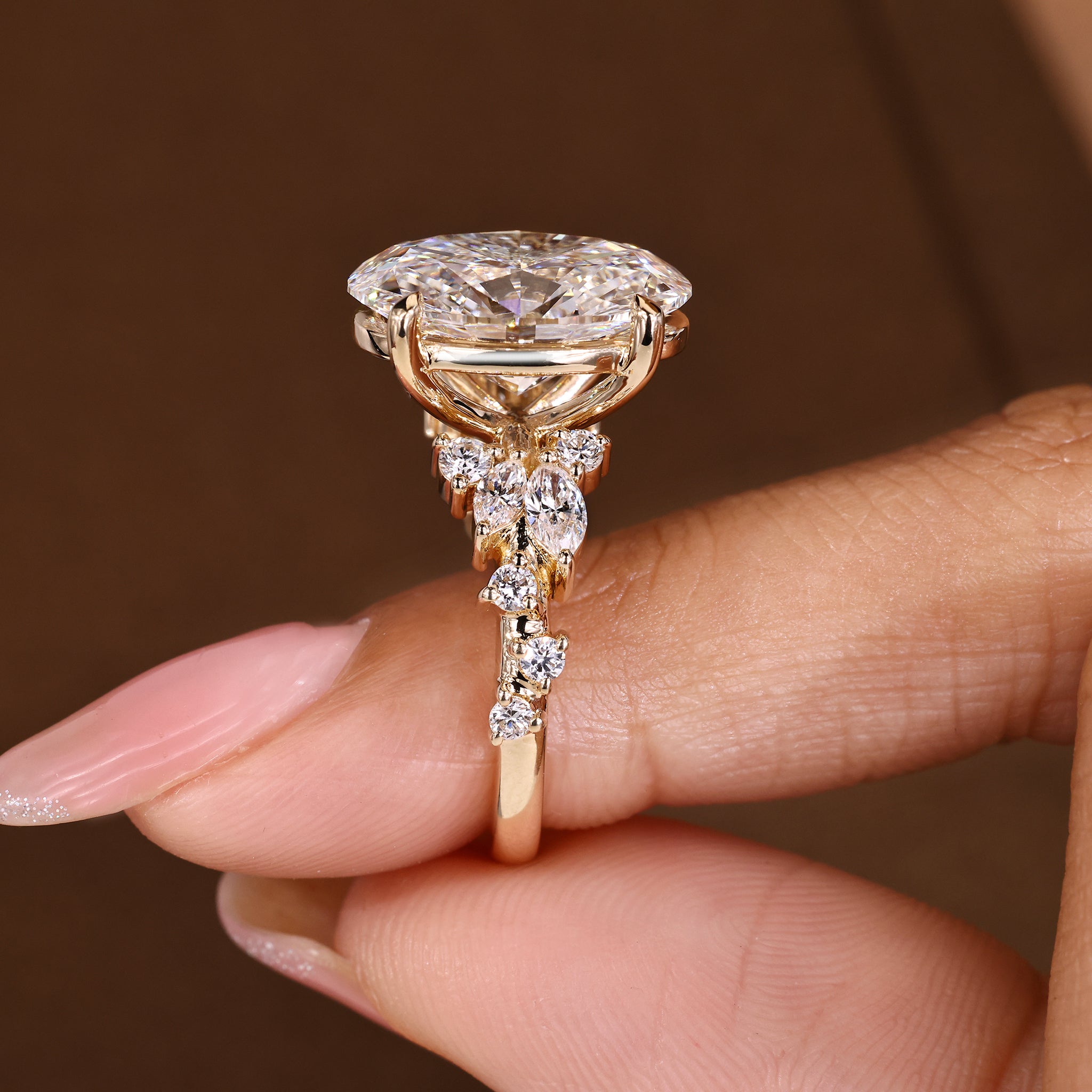 Lab grown oval cut diamond ring in a detailed marquise and round cluster setting.
