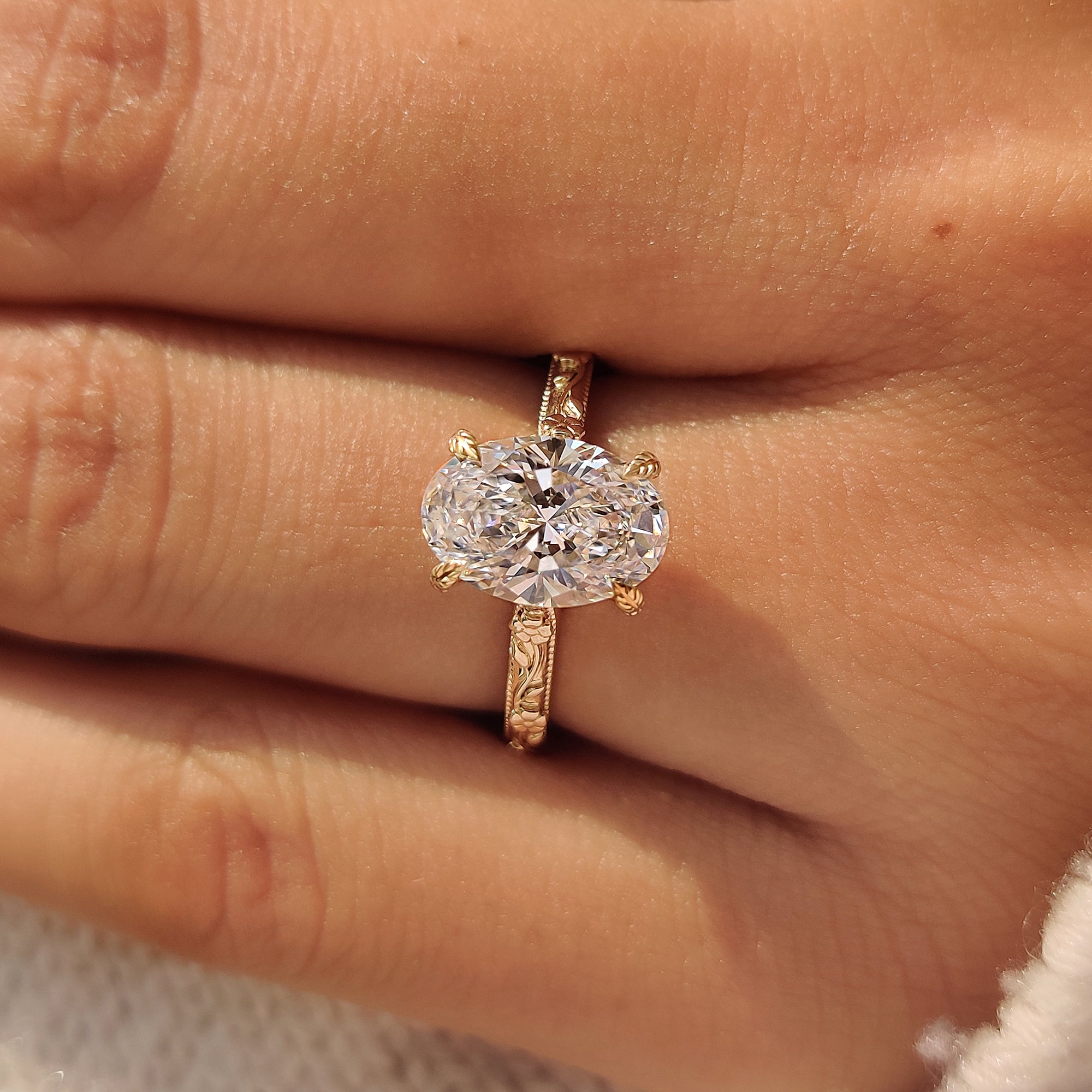 Yellow gold hidden halo engagement ring with floral engraving.
