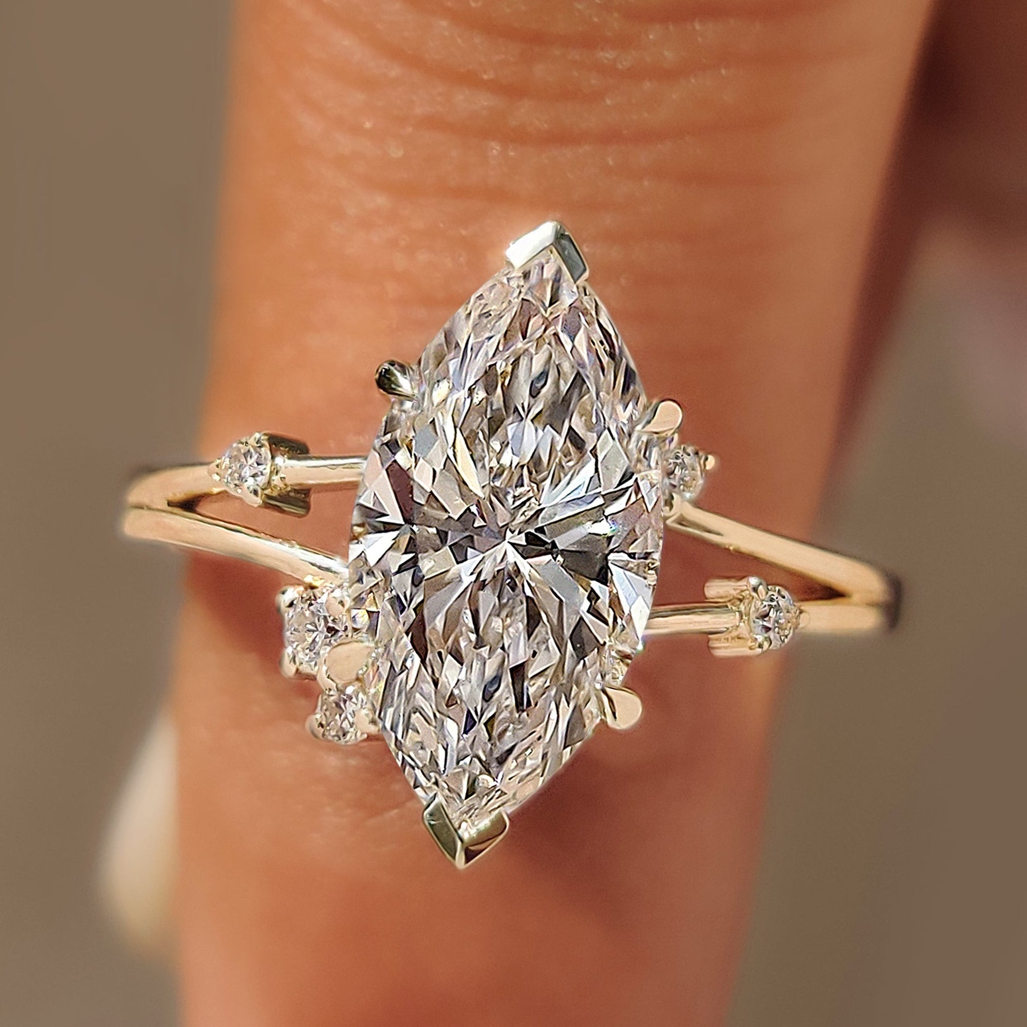 Split shank engagement ring with marquise diamond and round side stones.
